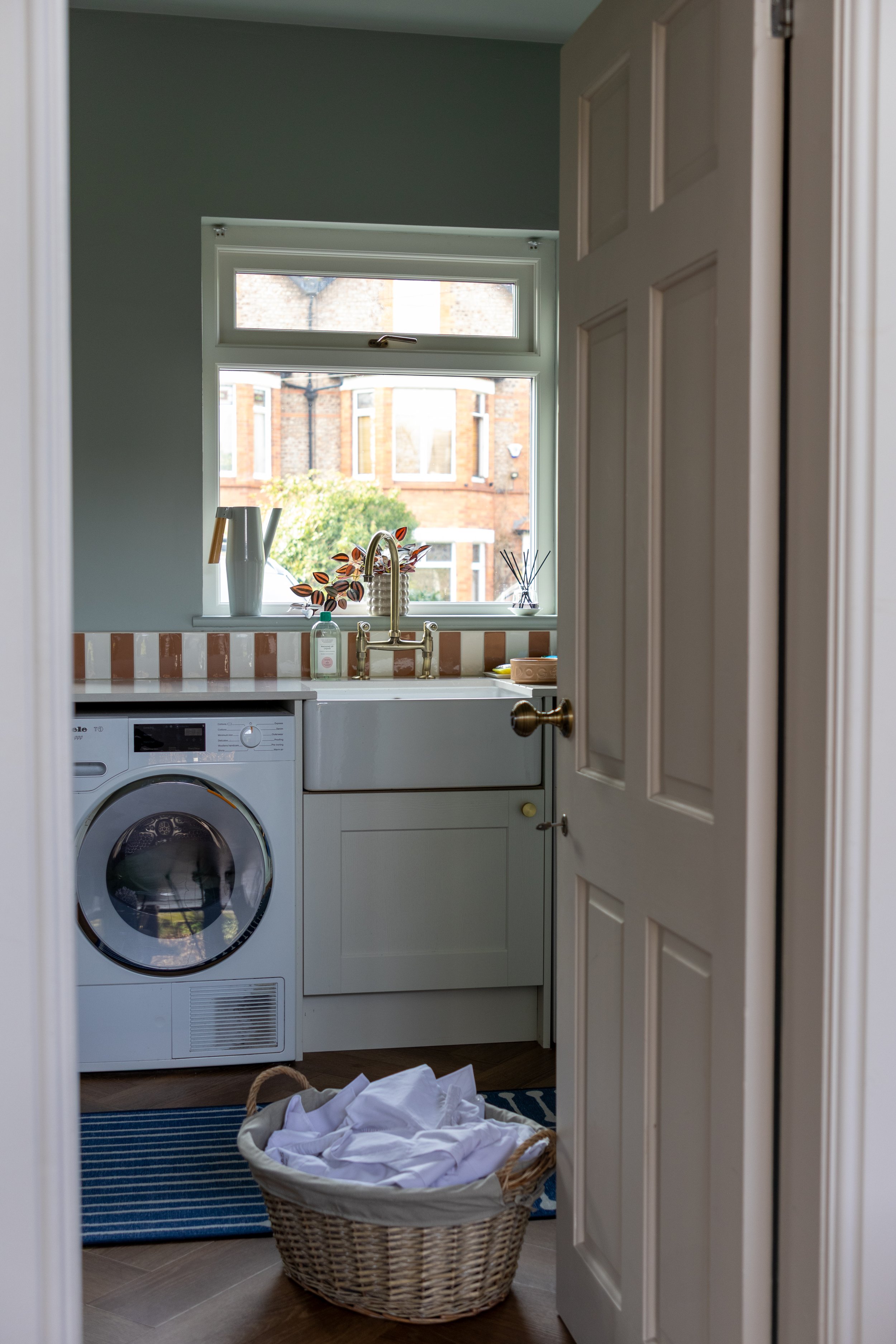 Utility room with washing machine, Belfast sink and terracotta striped tiles seen through open door