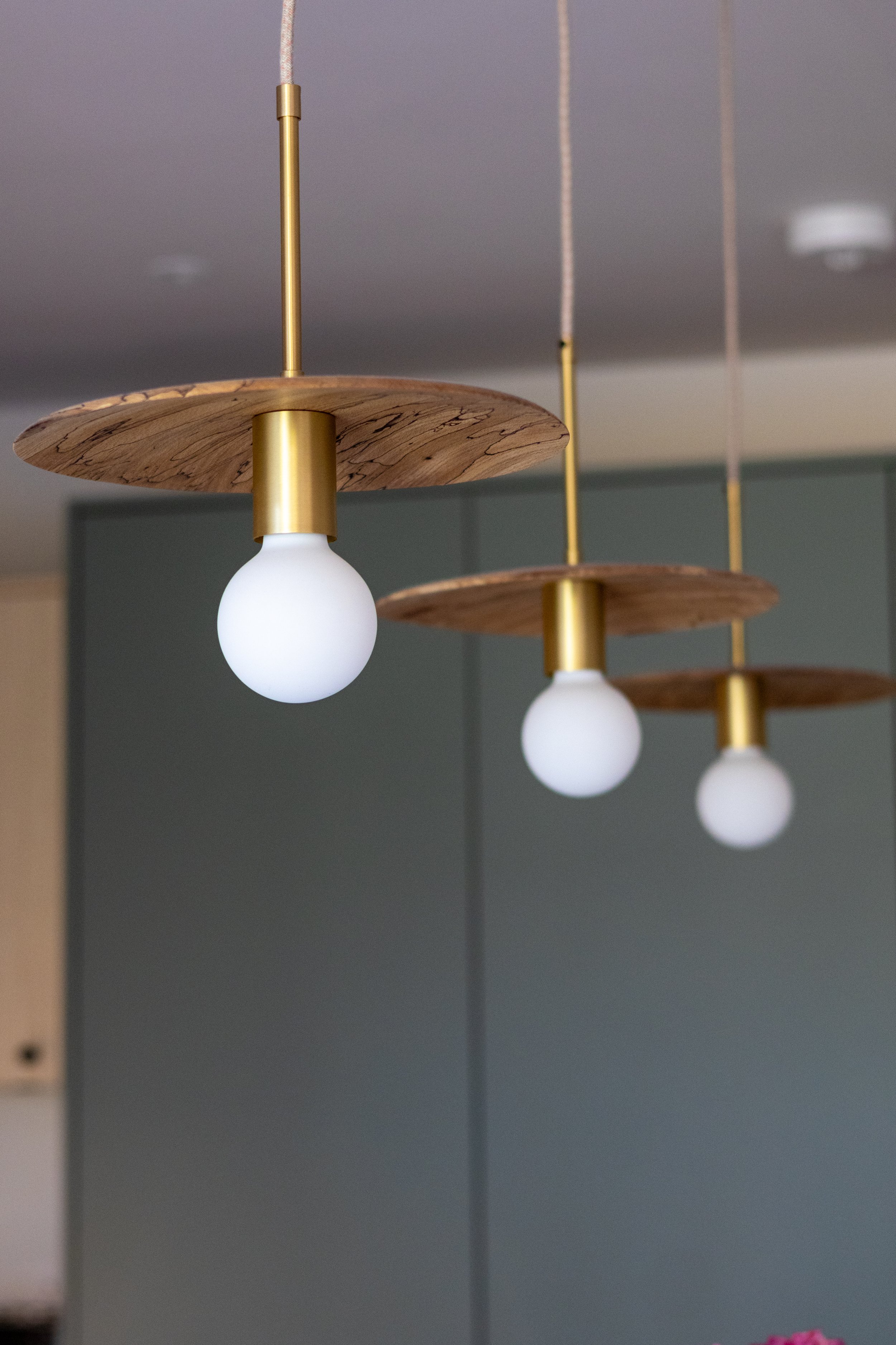 Close-up of brass and timber disc pendant lights with exposed bulbs