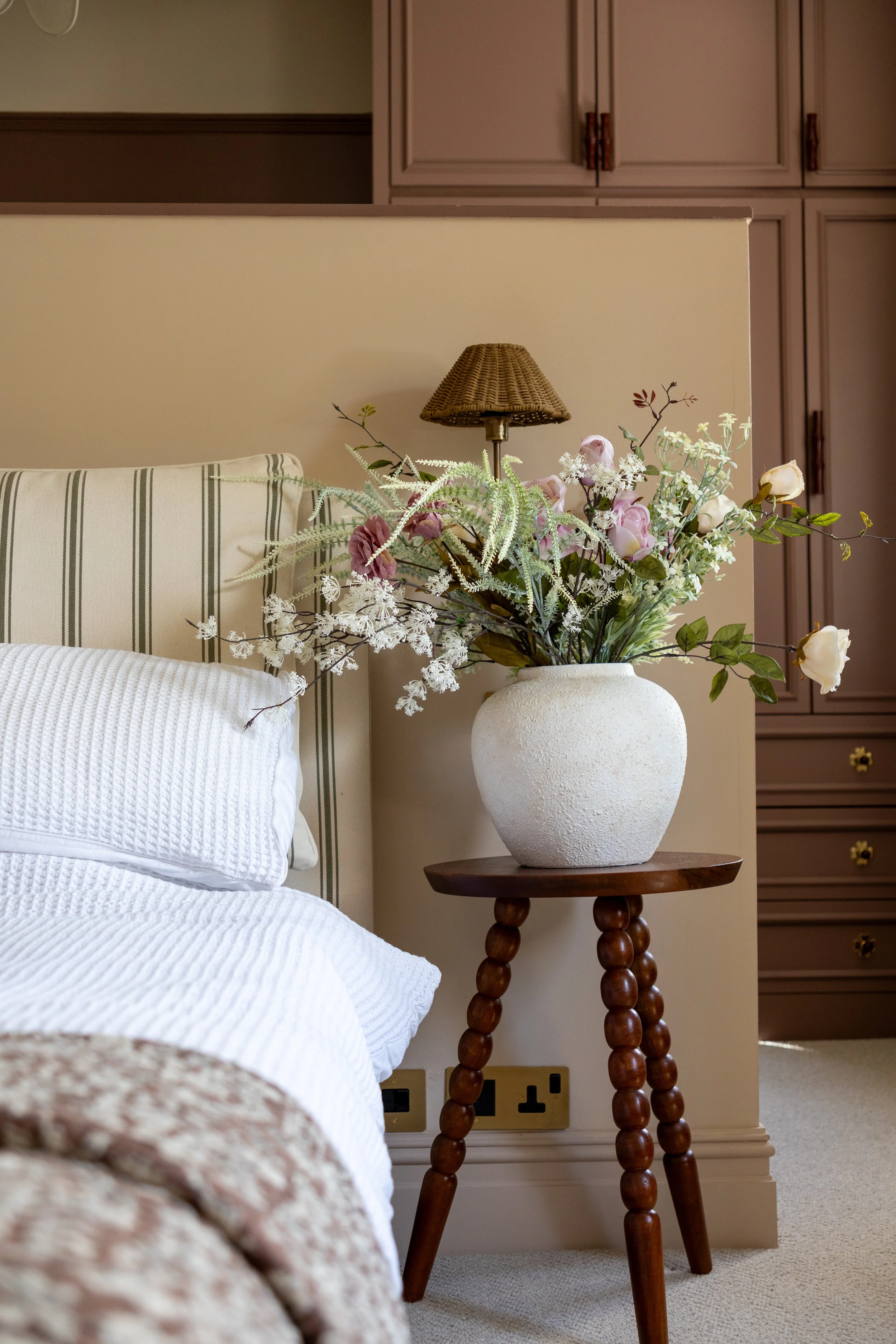 Bobbin-leg side table holding a textured cream vase with pink and white floral