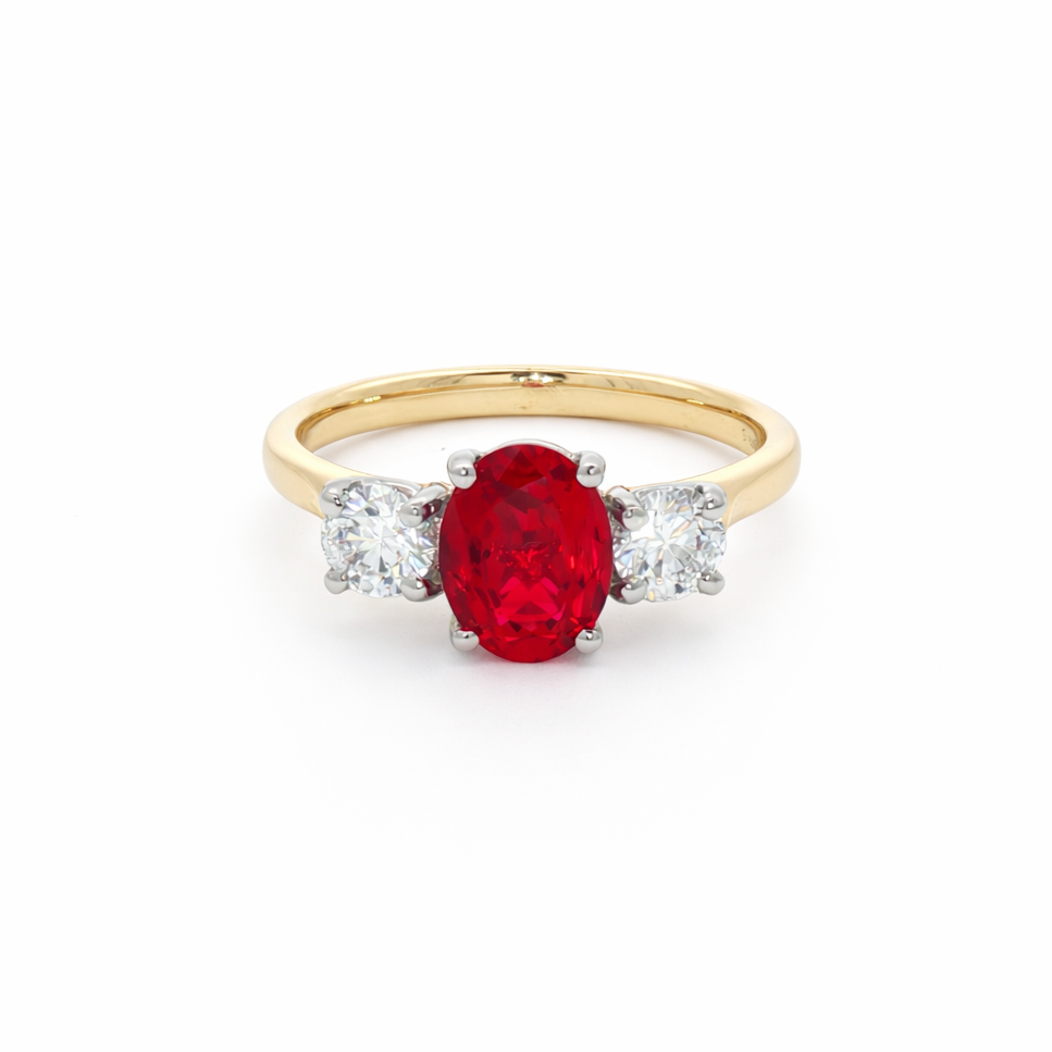 Gold ring with an oval red gemstone flanked by two round clear diamonds on each side against a white background.