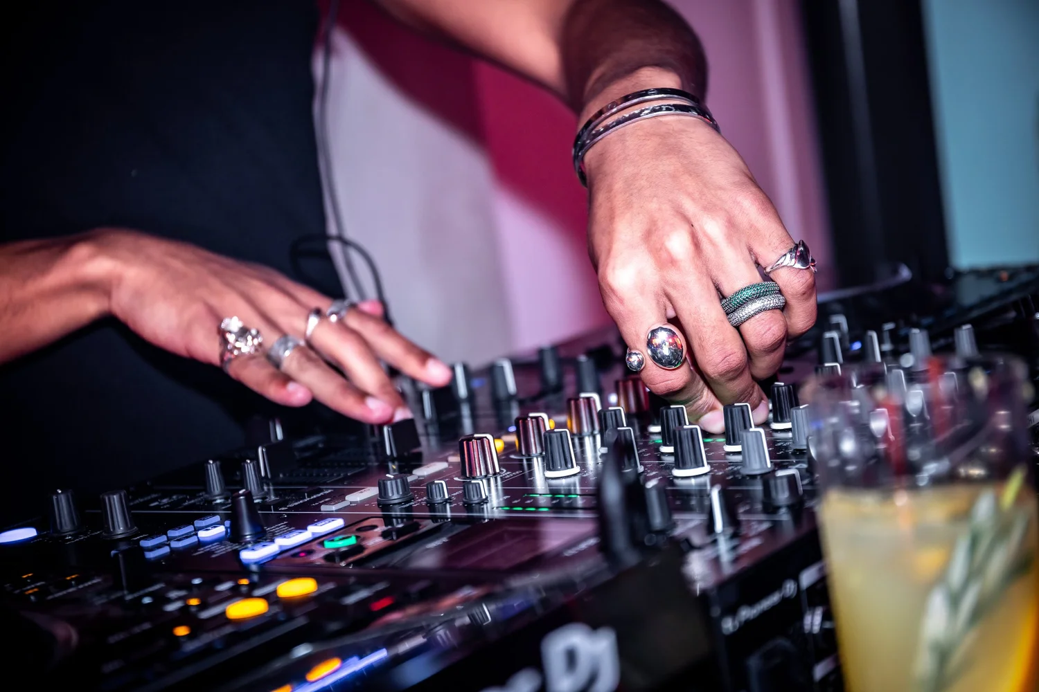 DJ hands on the mixer with rings and shot glasses