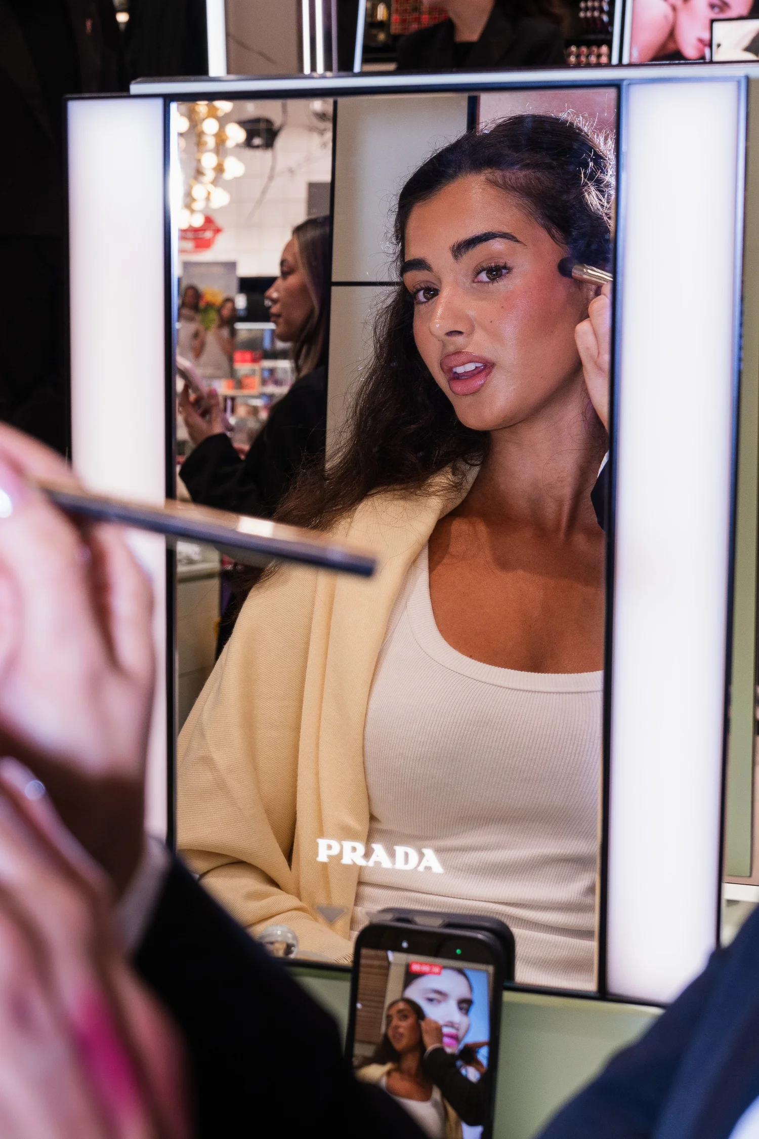 Guest in the illuminated mirror during a Prada makeup touch-up
