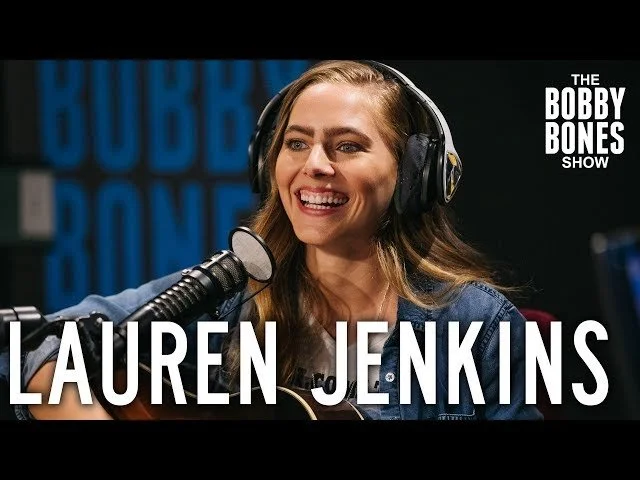 Lauren Jenkins smiling while recording on The Bobby Bones Show with headphones and microphone.