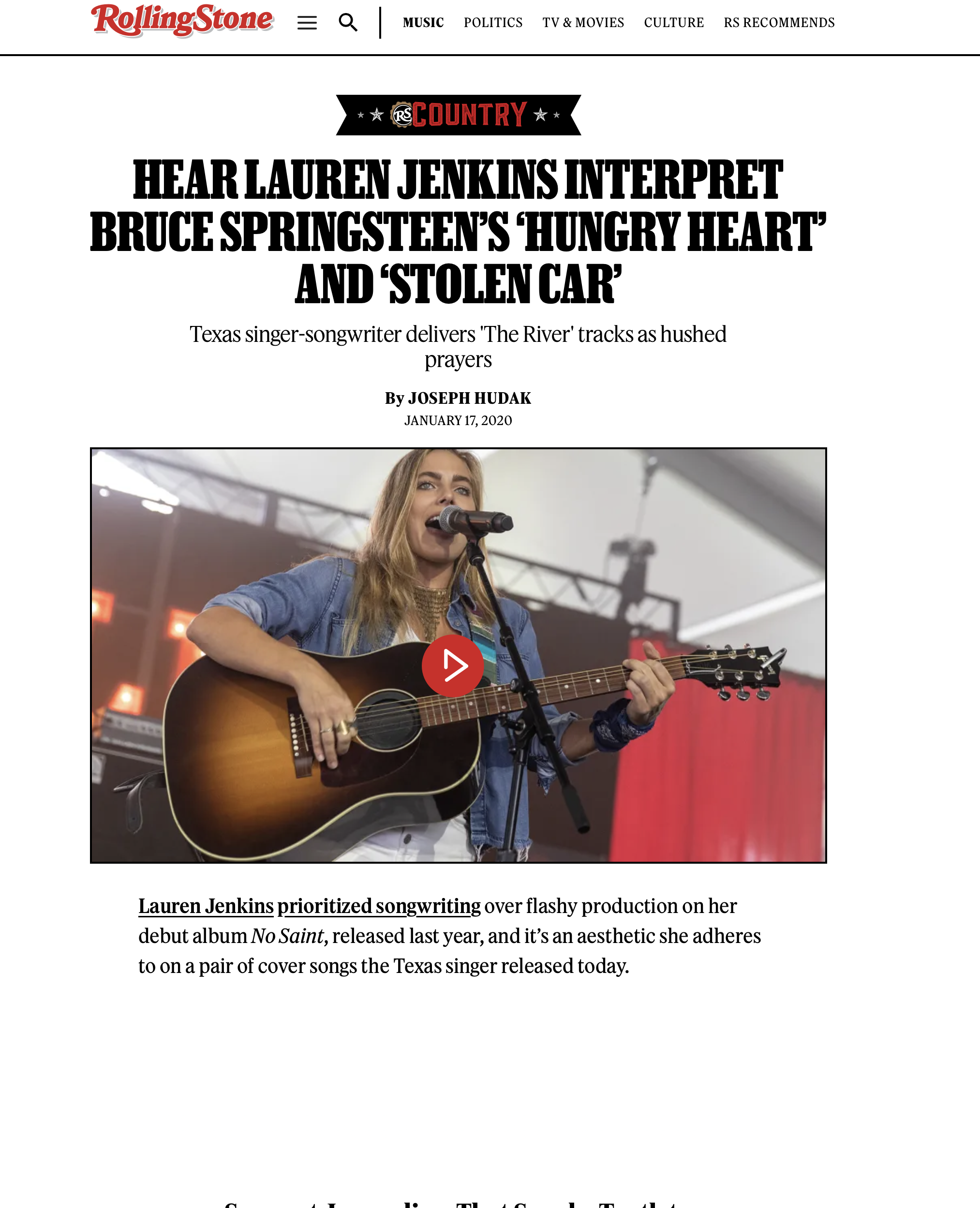 Lauren Jenkins singing and playing an acoustic guitar on stage during a performance.