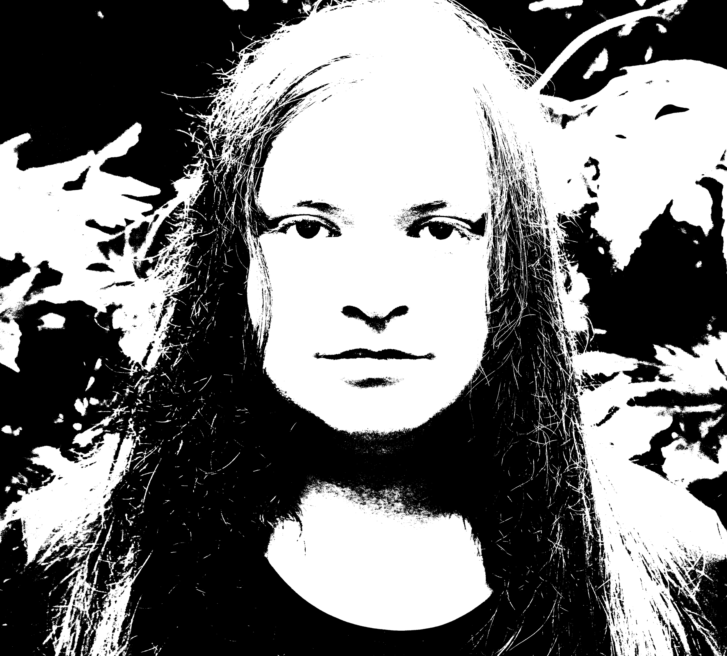 Black and white high-contrast portrait of a person with long hair against a leafy background.