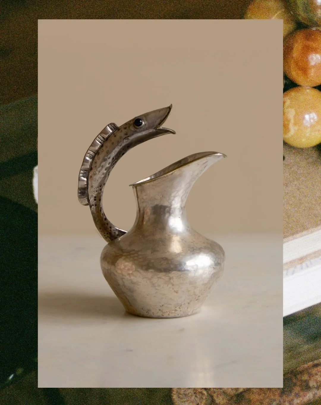 Available | A rare and beautifully sculptural silver plate pitcher with a carved fish handle.

Dating to the 1960&rsquo;s this piece was made in Taxco, Mexico by Los Castillo. The fish is detailed with black agate stone eyes, the pitcher has a hammer