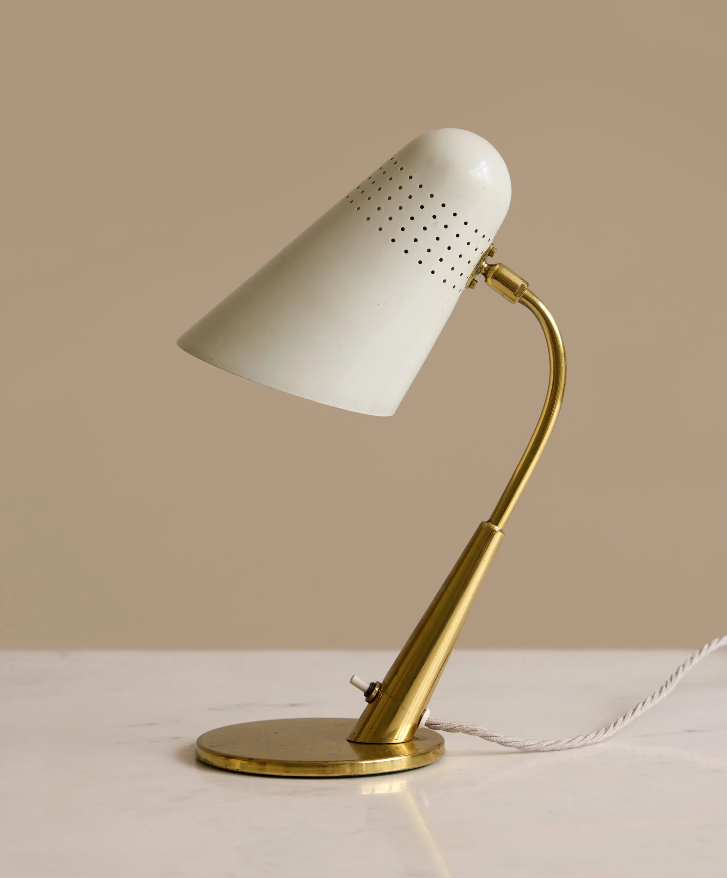 Available | A rather beautiful cream and brass small Italian table lamp. 

The lamp features an adjustable shade mounted on a ball joint, allowing for a wide range of positioning. This guy is both elegant and functional, perfect for elevating a works