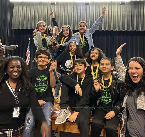 Students celebrating a competition win with trophies