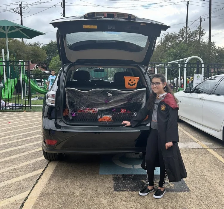 Student in costume beside a decorated SUV