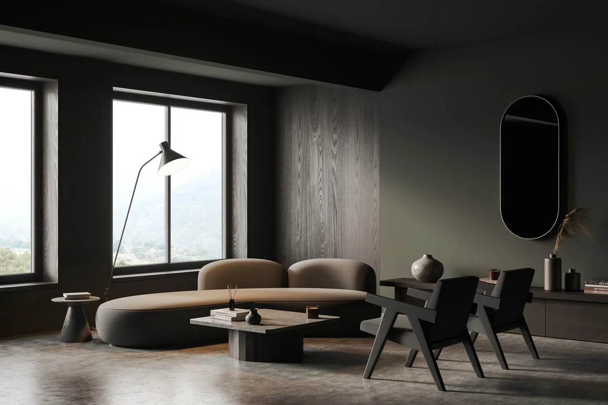 Modern living room with large windows, beige curved sofa, black chairs, gray room decor, and minimalist accessories.