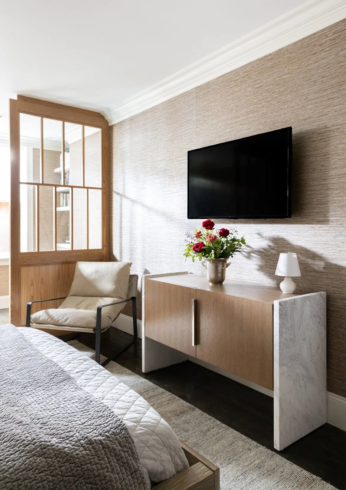 Wide shot of a modern loft bedroom showing the custom reading nook alongside a built-in light brown and marble media console.
