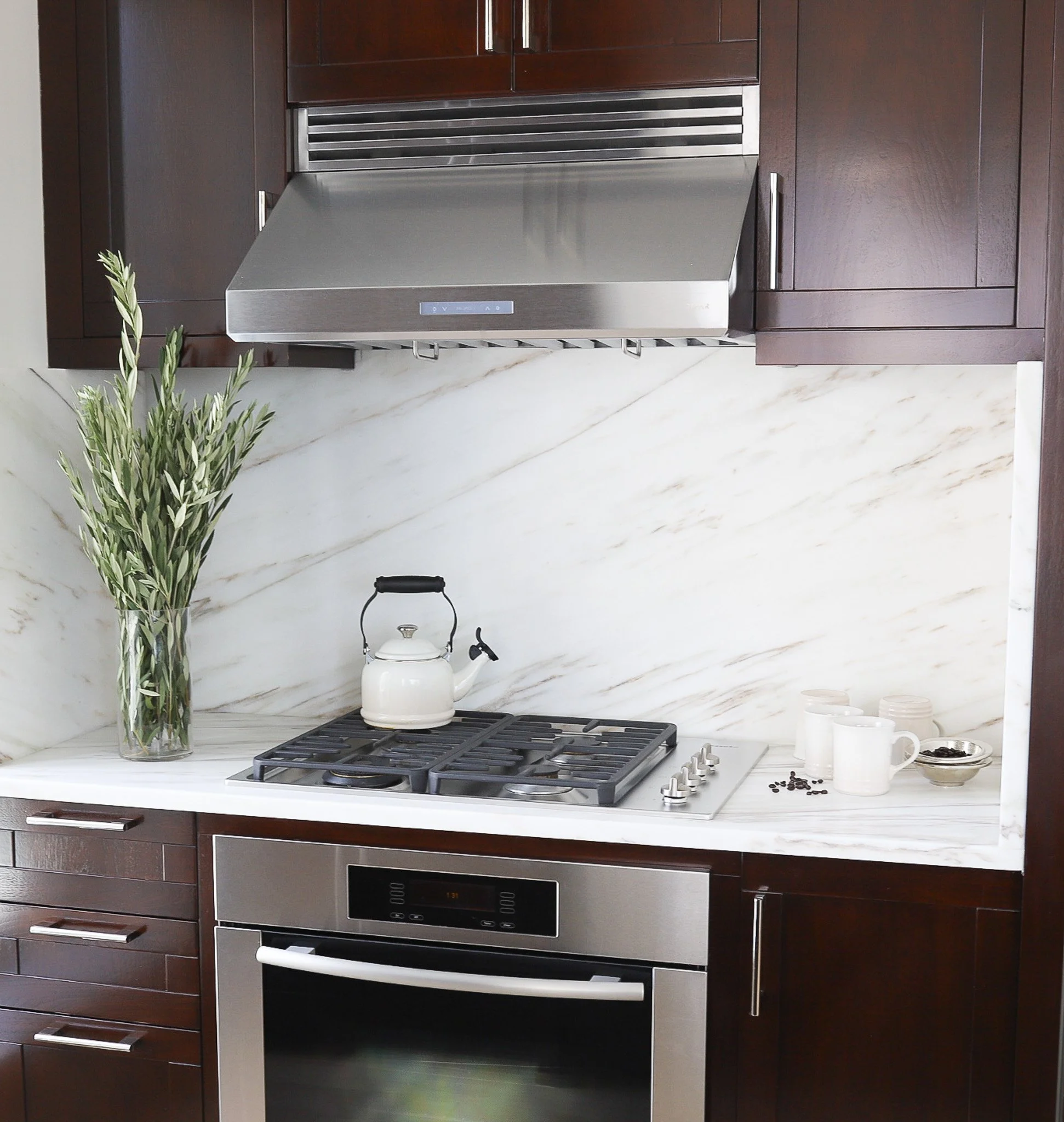 Close-up of a high-end kitchen remodel showing a modern stove-top, integrated oven, and dark wood custom cabinets.