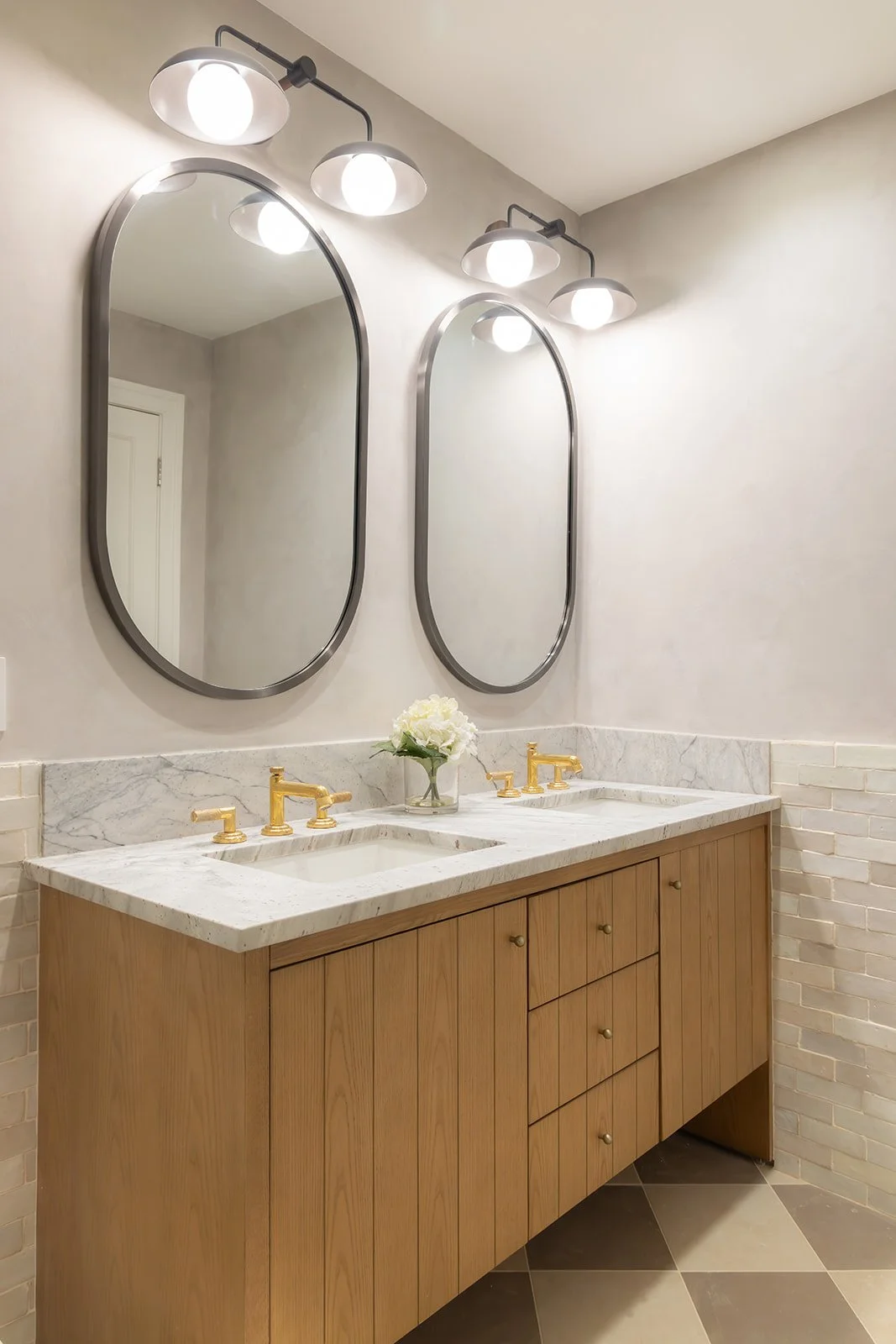 Side-angle close-up of a modern bathroom sink detailing a light marble vanity surface and sleek gold plumbing fixtures.