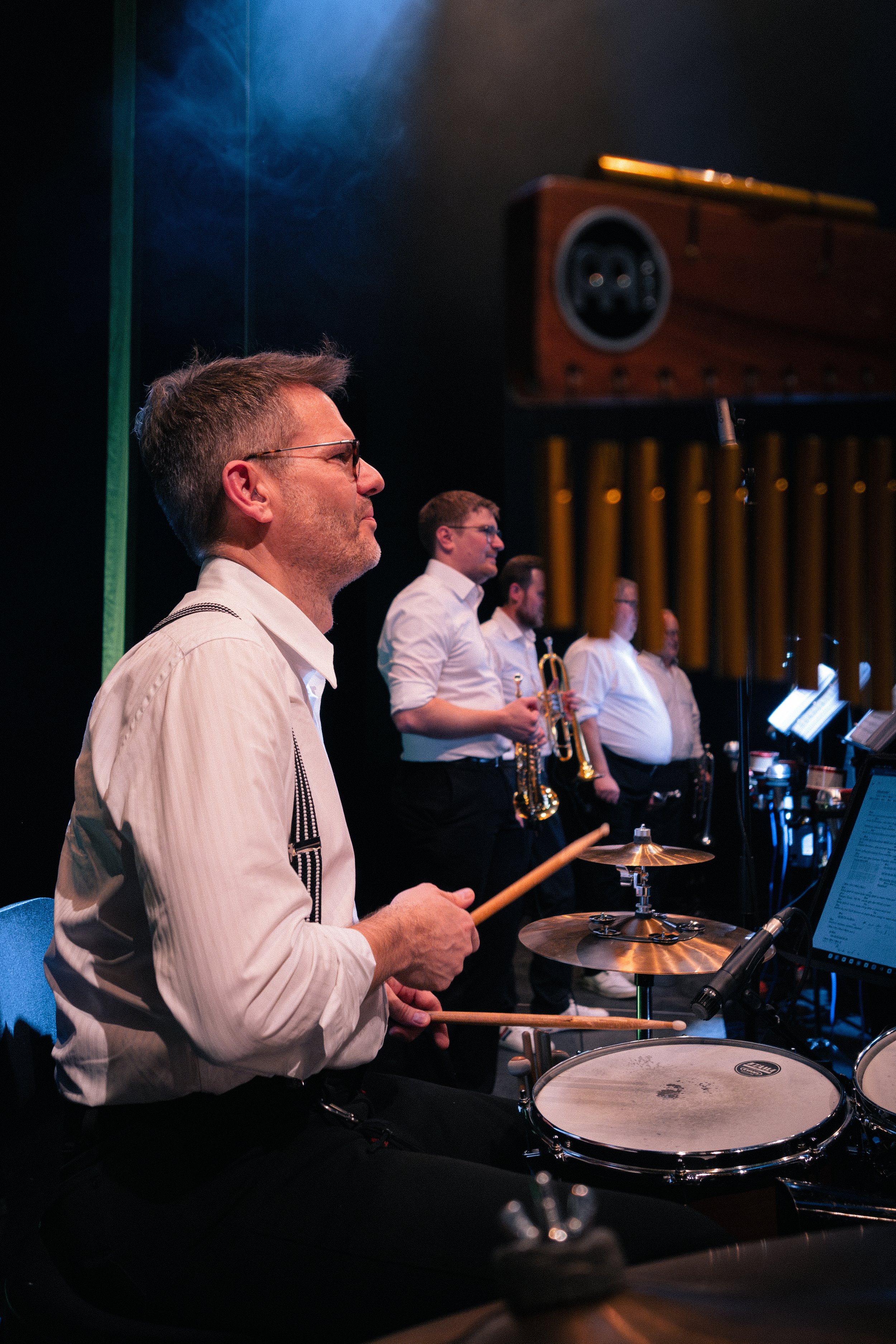 Ein Mann sitzt hinter einer Percussion mit einem Notenständer und einem Musikblatt, er lächelt.