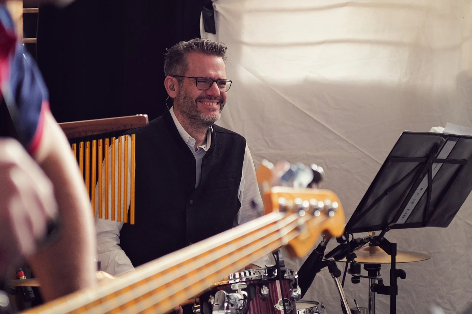 Ein Mann sitzt hinter einer Percussion mit einem Notenständer und einem Musikblatt, er lächelt.