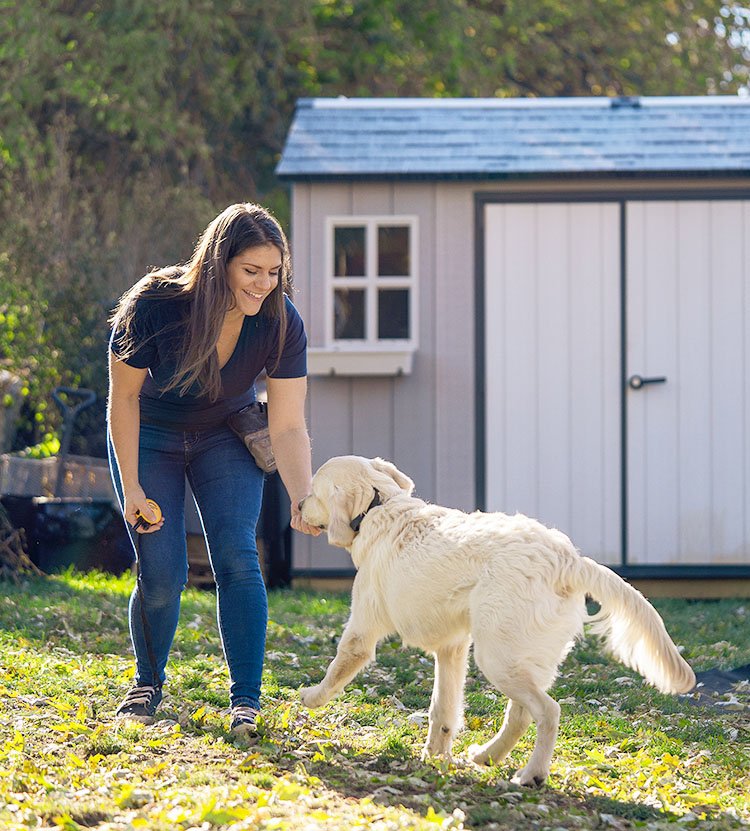 A female professional dog trainer with a dog at the front door.
