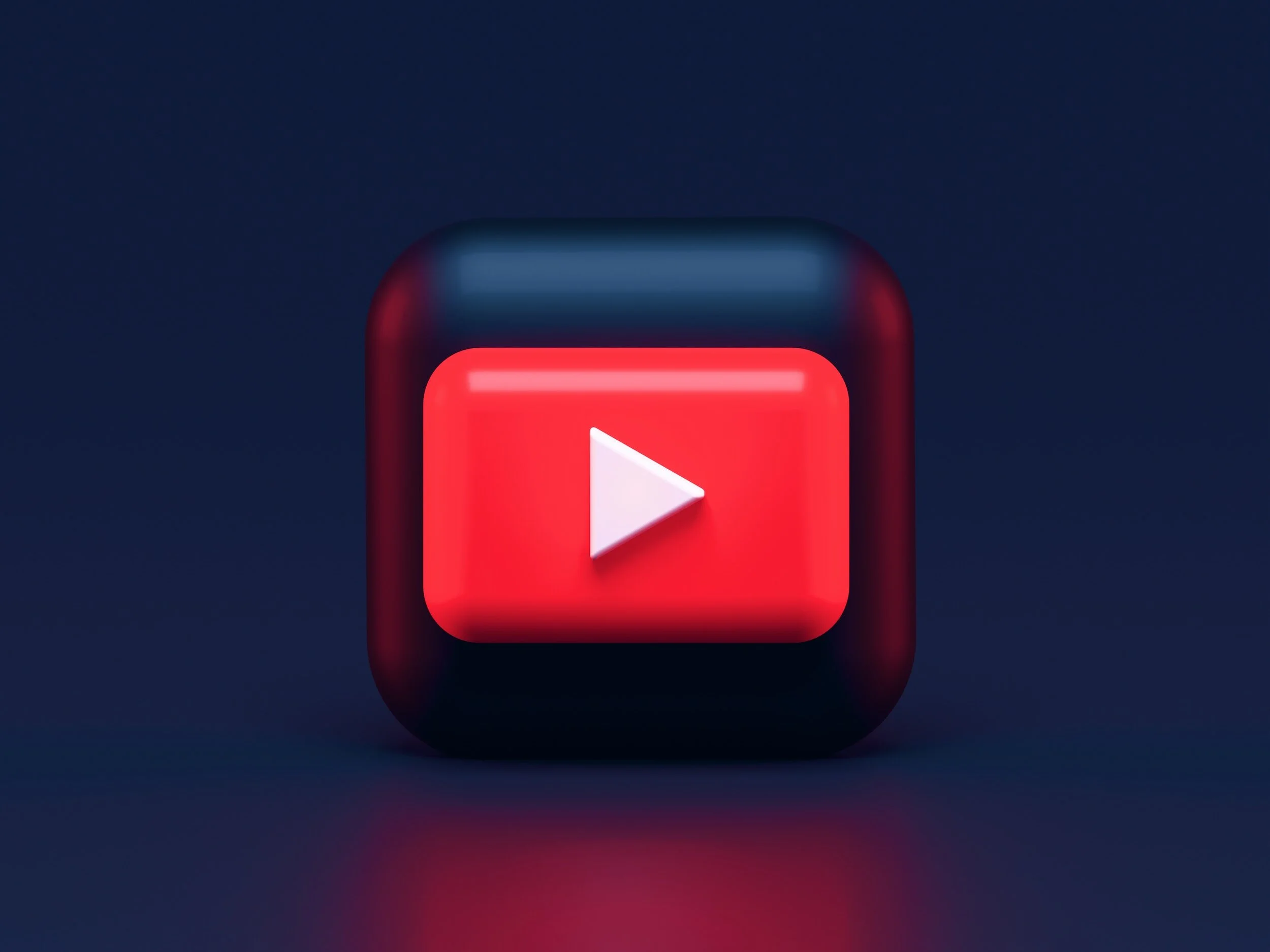 A close-up of a red YouTube play button icon on a dark background with a subtle glow.