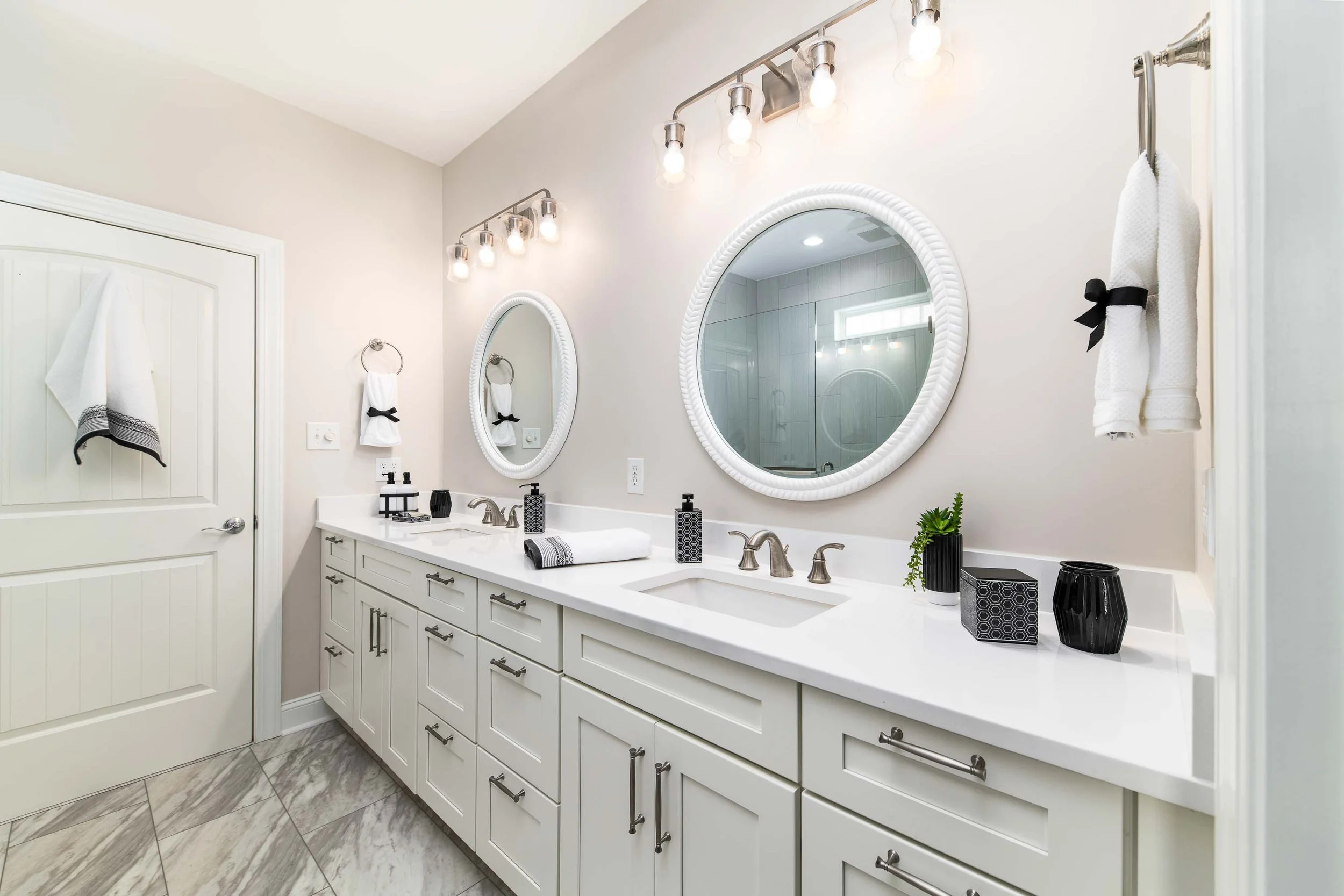 Chic white bathroom remodel with round mirrors in Eastern NC