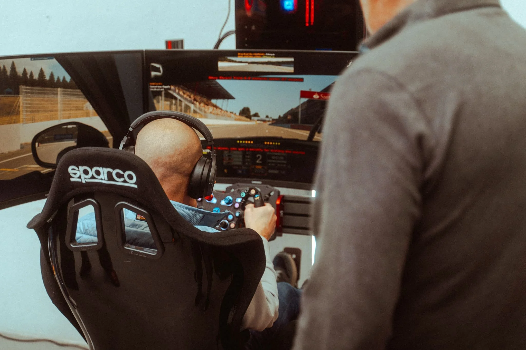 Persoon rijd op een race simulator waarbij hij rijd in de Porsche 911 GT3 R  (992) op Spa-Francorchamps.