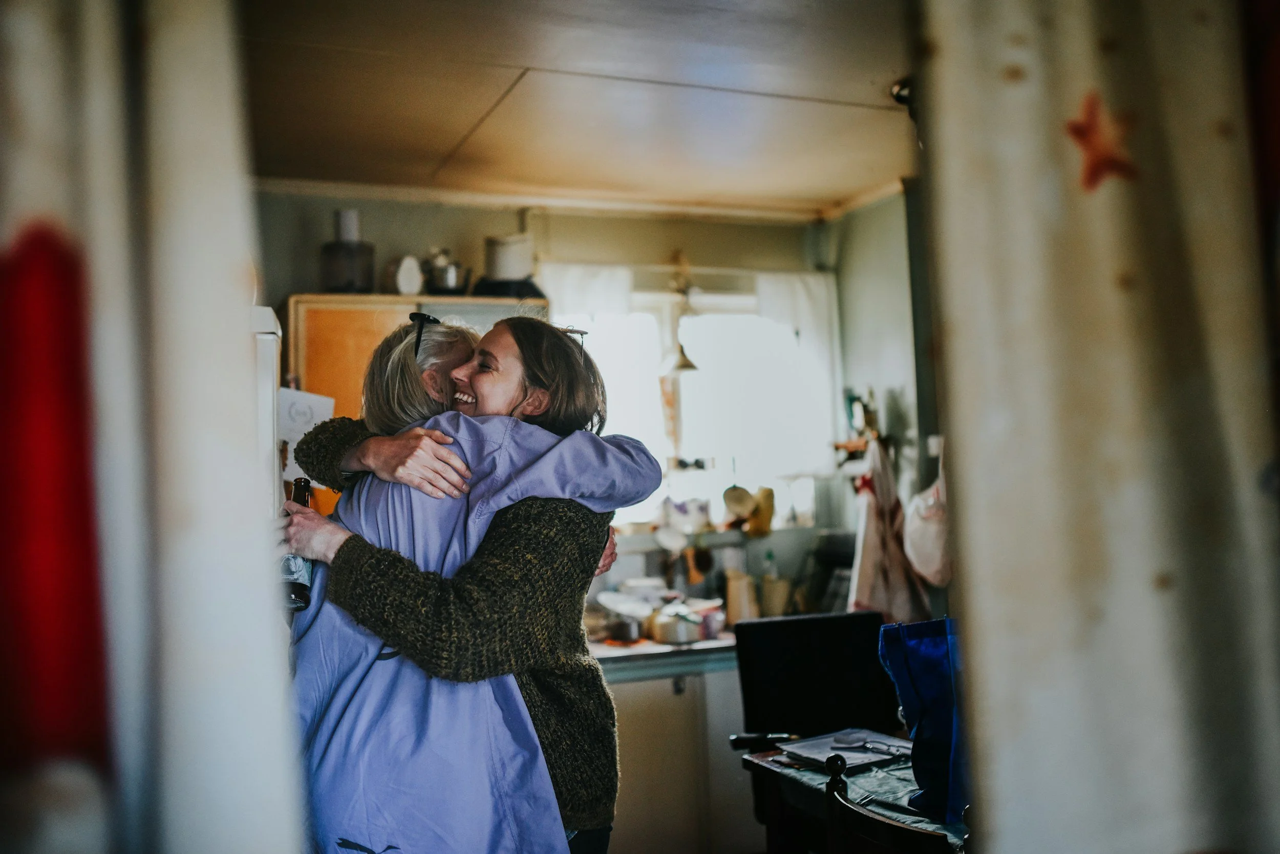 Two women warmly hugging in a cozy home.
