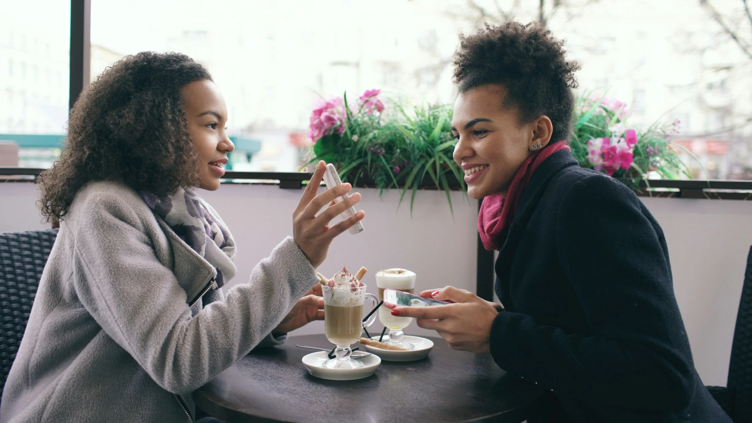 Two women chatting over coffee and dessert at a cafe table