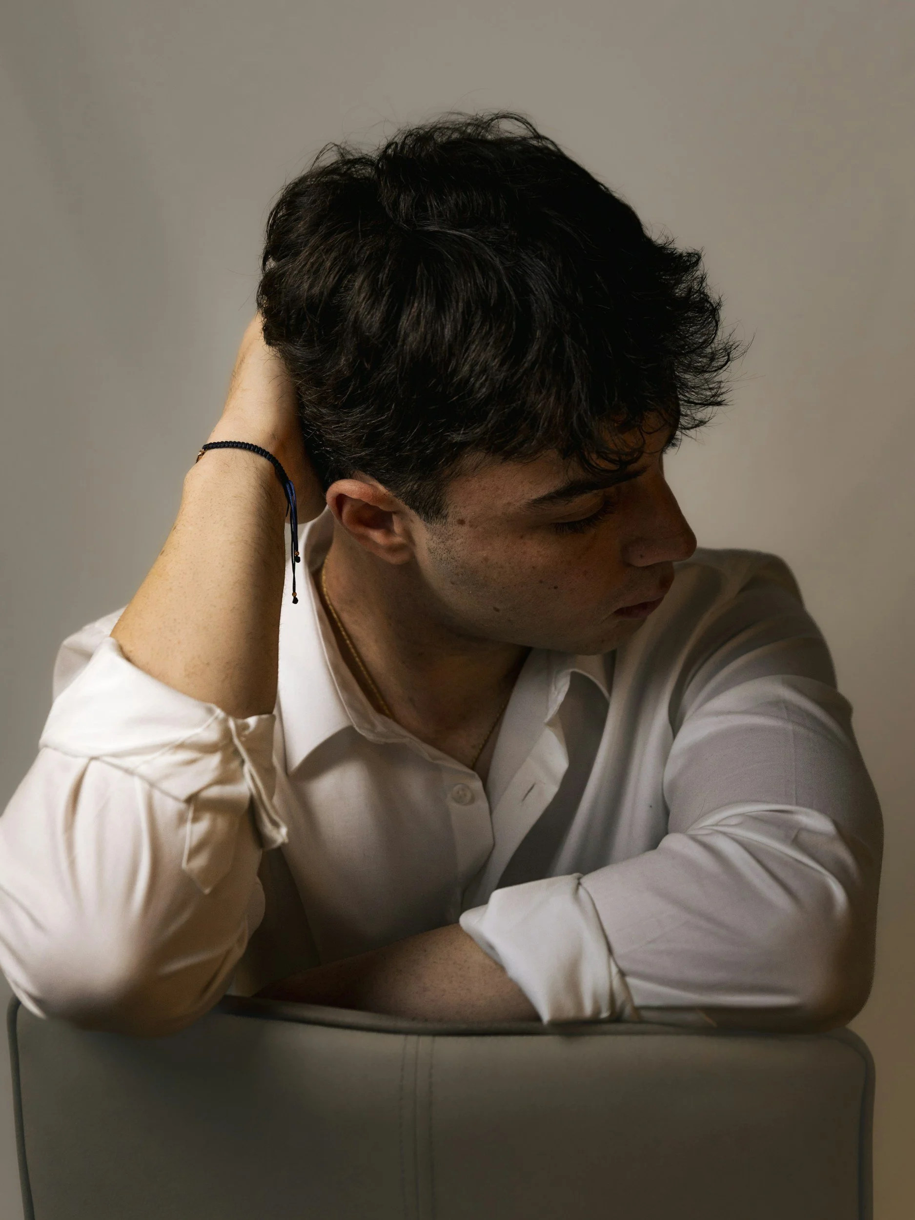 Man in a white shirt sitting in a chair with his hand behind his head