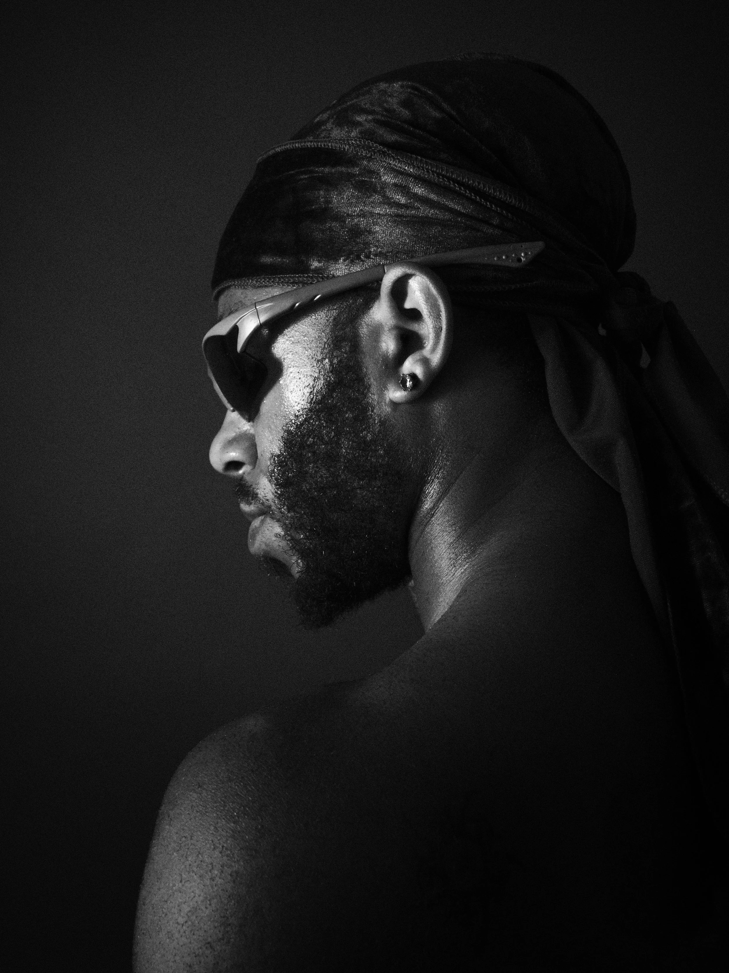 Profile of a man with a beard wearing sunglasses and a bandana, shot in black and white.