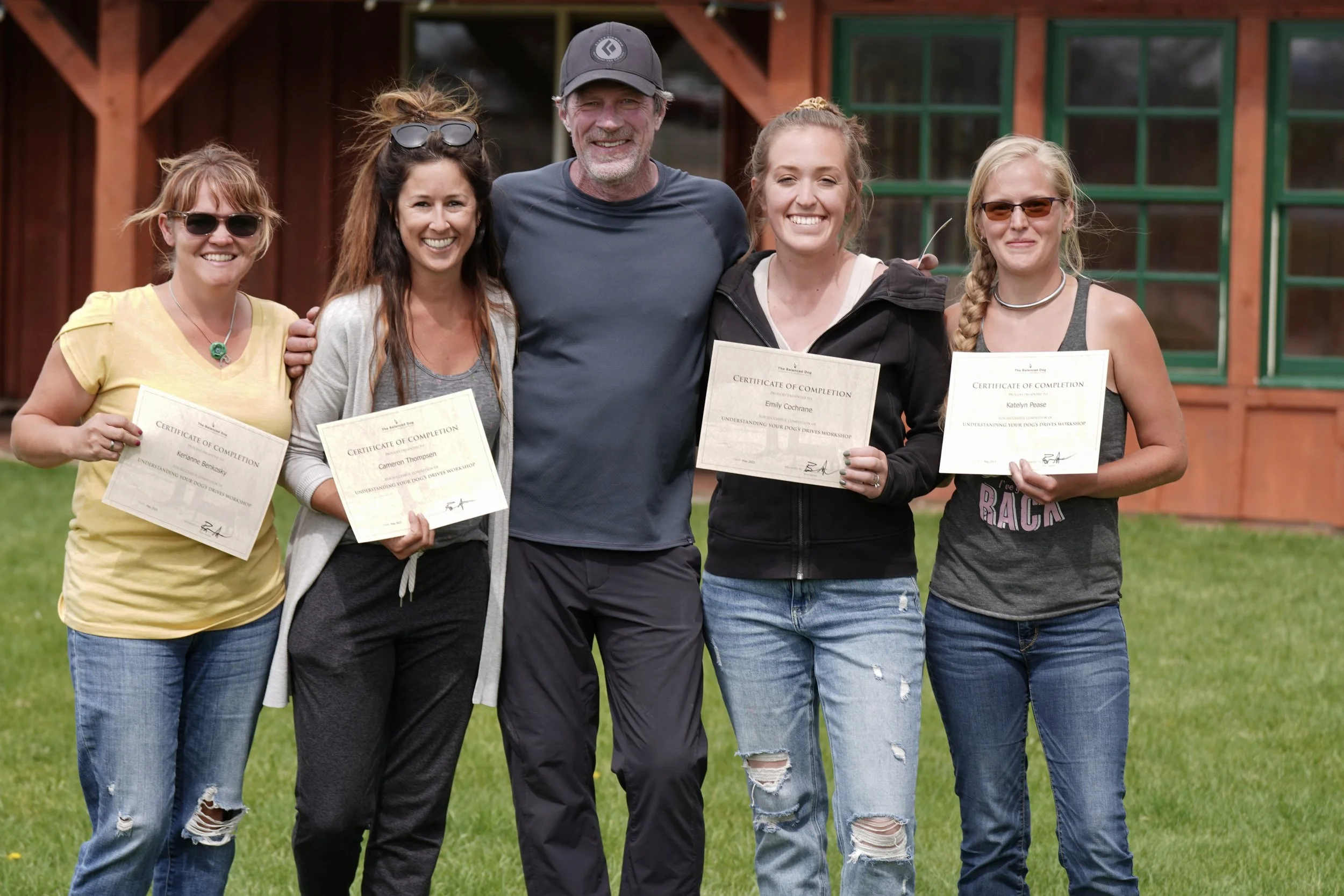 Five smiling adults pose outdoors holding certificates of completion from a Lucas Agnew dog training workshop. Far right person is Katelyn.