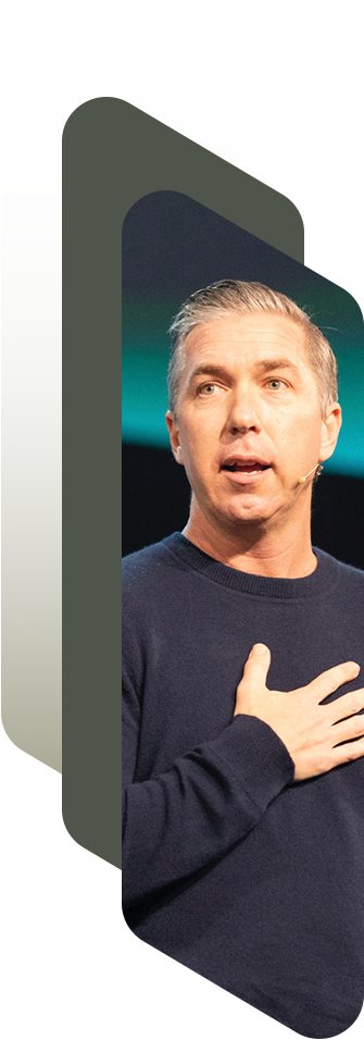 Steve Carter at an event, wearing a dark sweater, with his hand placed over his chest, and a microphone headset.