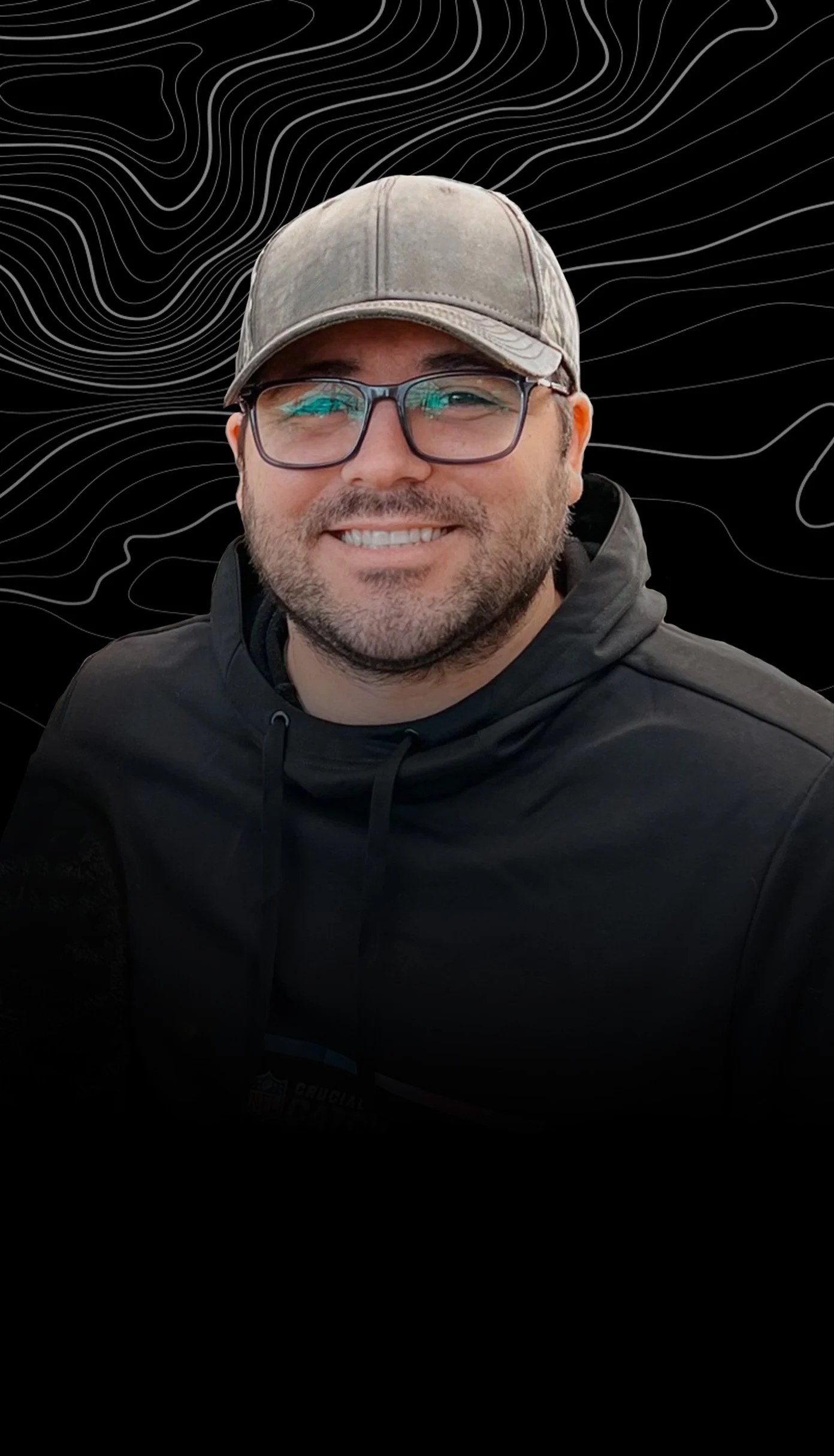 Michael Birky wearing glasses, a gray cap, and a black hoodie, with a black background featuring white contour lines.