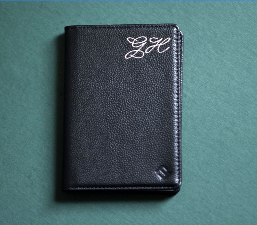 Black textured wallet with monogram initials 'GHC' embroidered in white on a green surface.