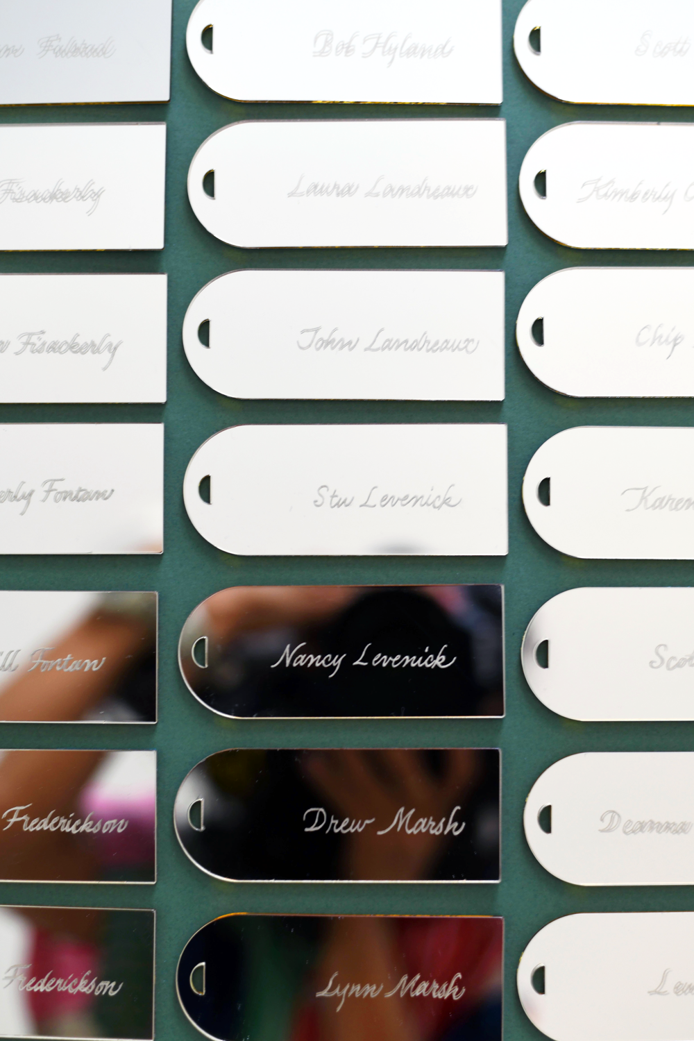 Close-up of a display of metal name tags with handwritten names in cursive font. The names include Nancy Levenick, Drew Marsh, and Lynn Marsh.