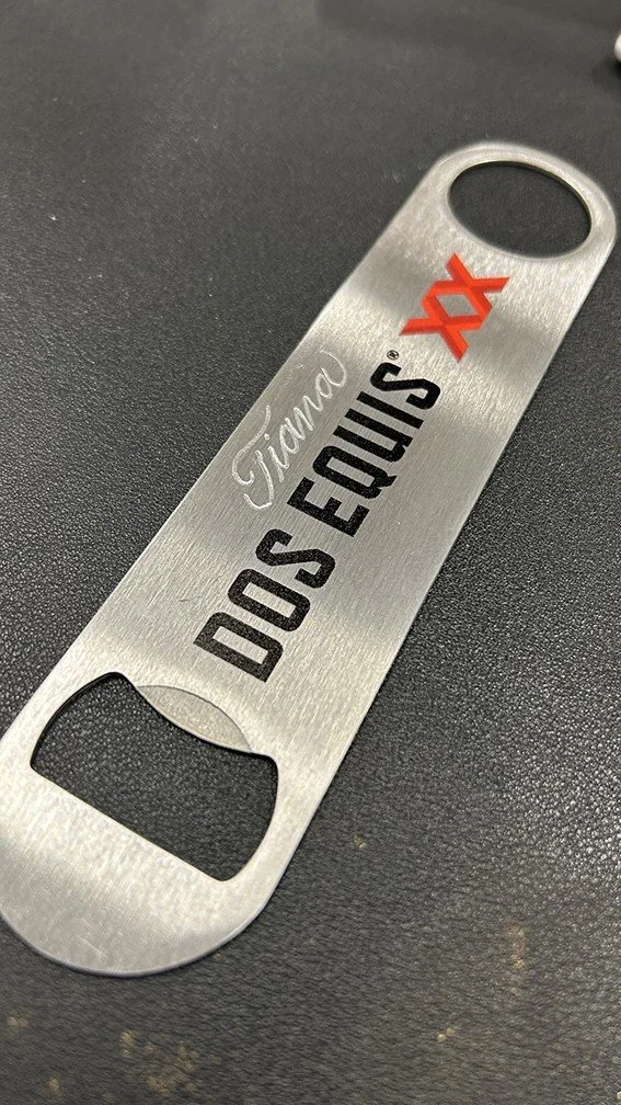 A metallic bottle opener with the text 'Tijuana DOS EQUIS' and a red X logo.
