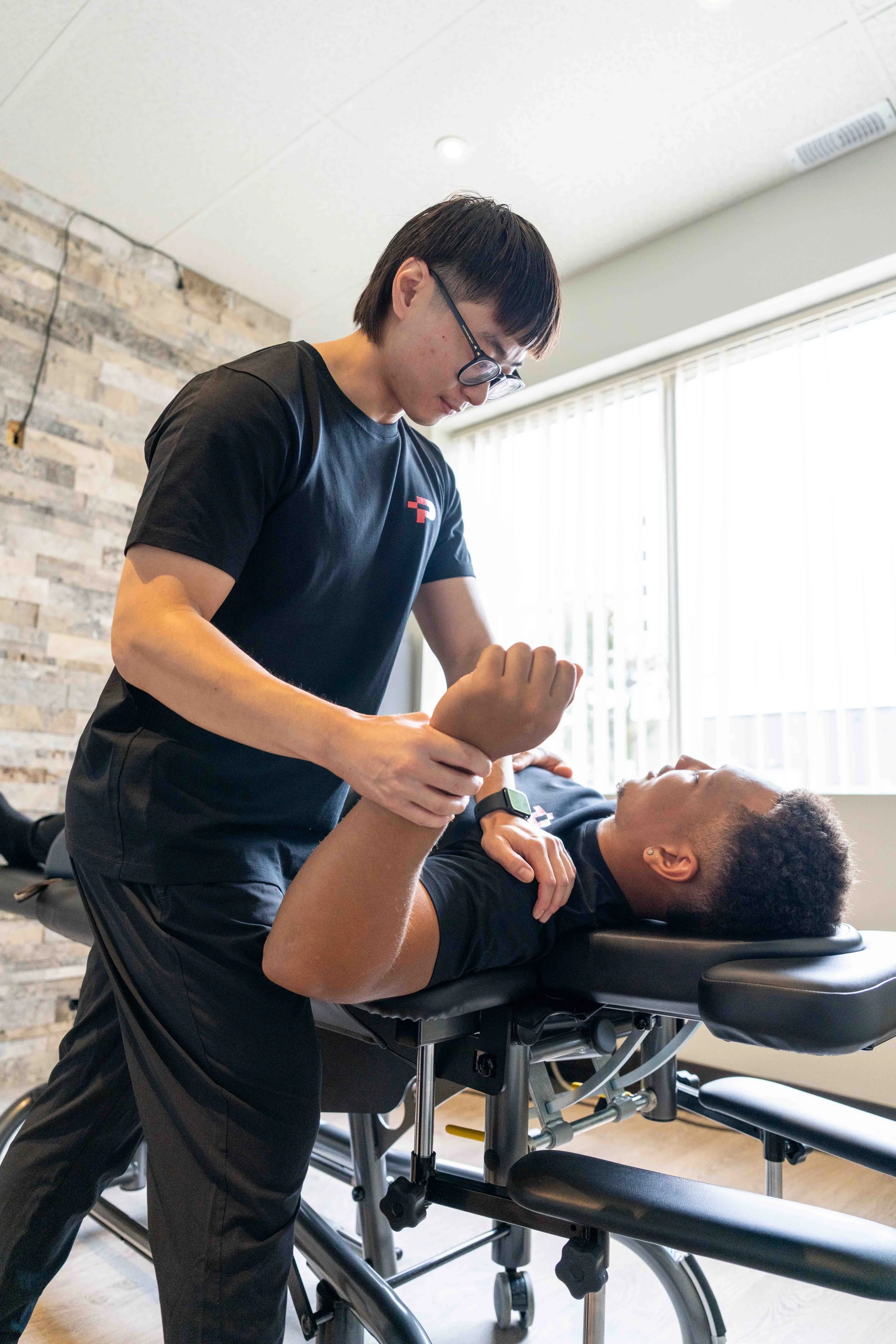 A physical therapist works with a patient on arm exercises in a medical clinic.