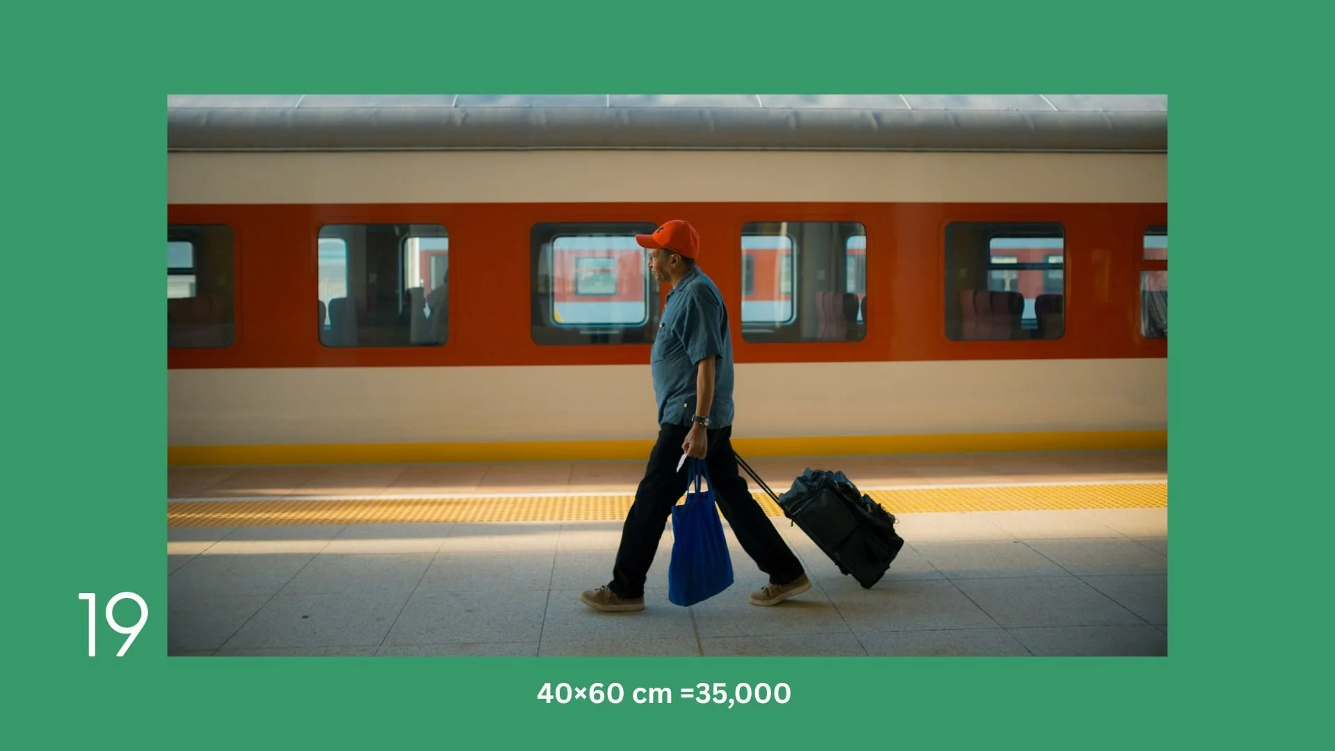 A man walking on a train station platform with luggage, wearing a red cap and blue shirt, with a train in the background.