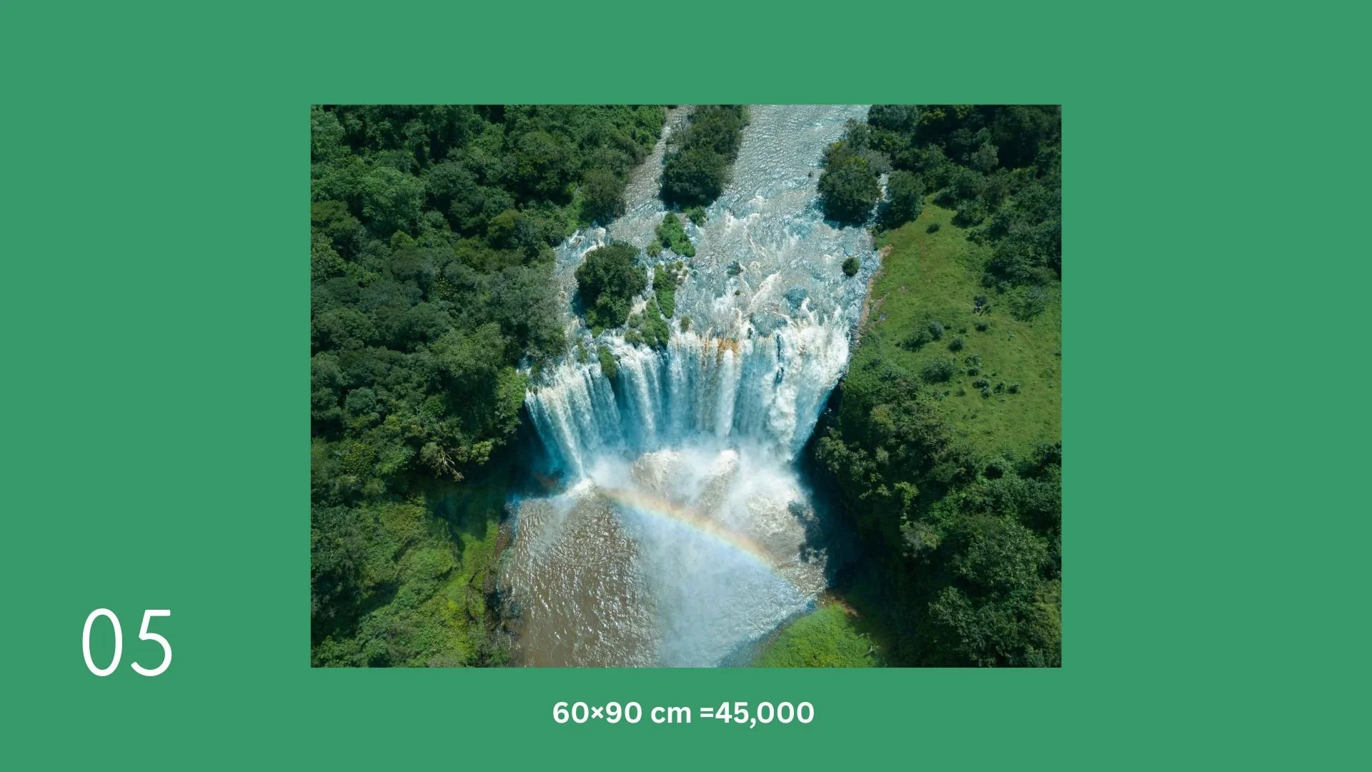 Aerial view of a waterfall surrounded by lush green trees and vegetation, with a rainbow visible at the base of the waterfall.