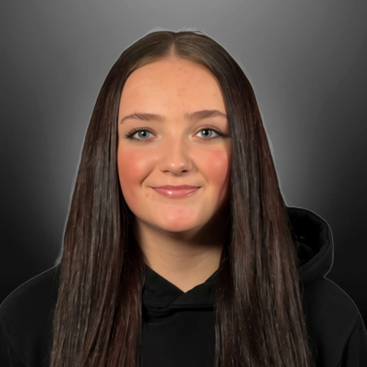 A young woman with long brown hair and blue eyes, smiling, in a black hoodie against a gray background.
