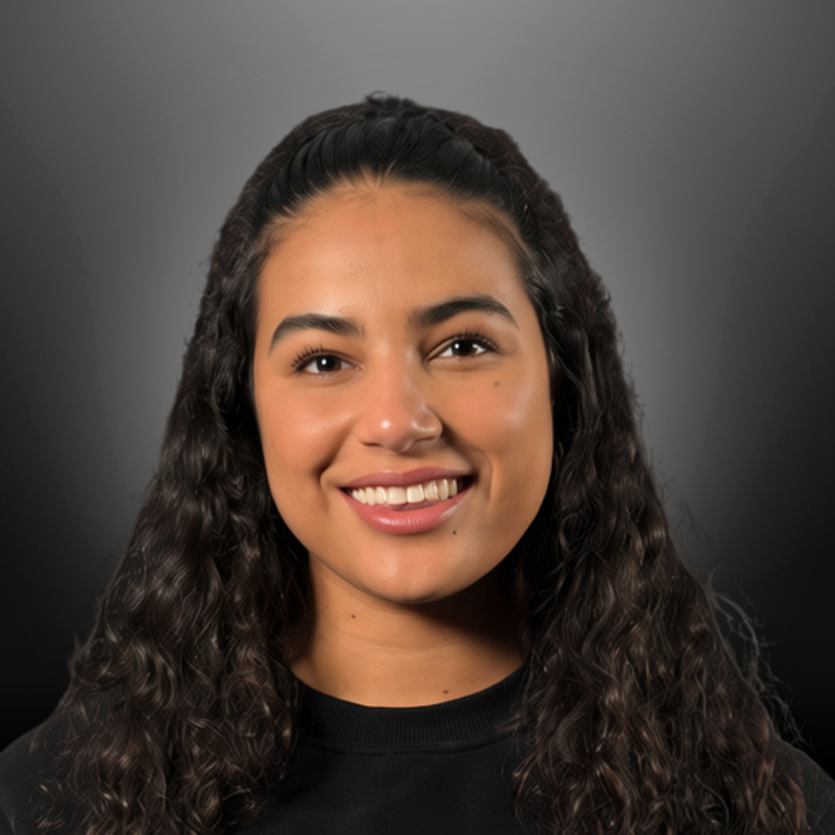 Portrait of a young woman with long, curly dark hair, smiling, wearing a black top, against a dark gradient background.