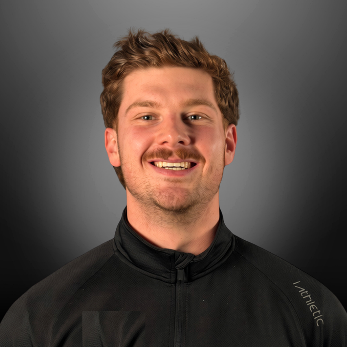 Young man with brown hair and a beard smiling, wearing a black athletic jacket with a high collar against a gray background.