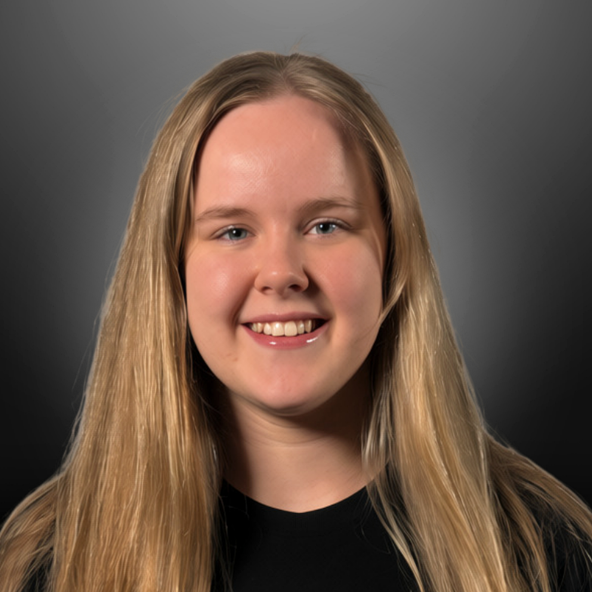 A young woman smiling, with long blonde hair, wearing a black top, against a gray gradient background.