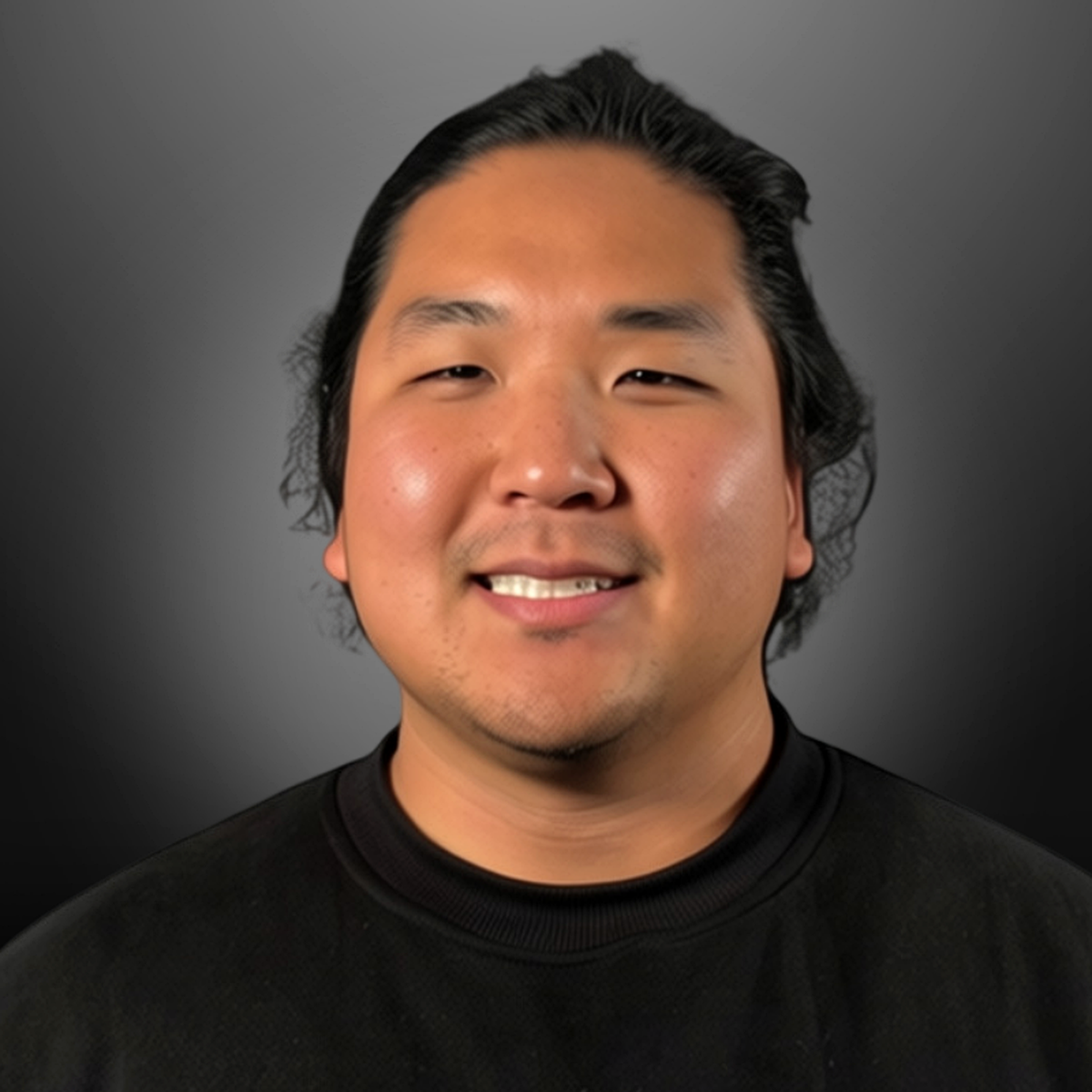 Portrait of a young man with black hair and a black shirt, smiling against a dark gray background.
