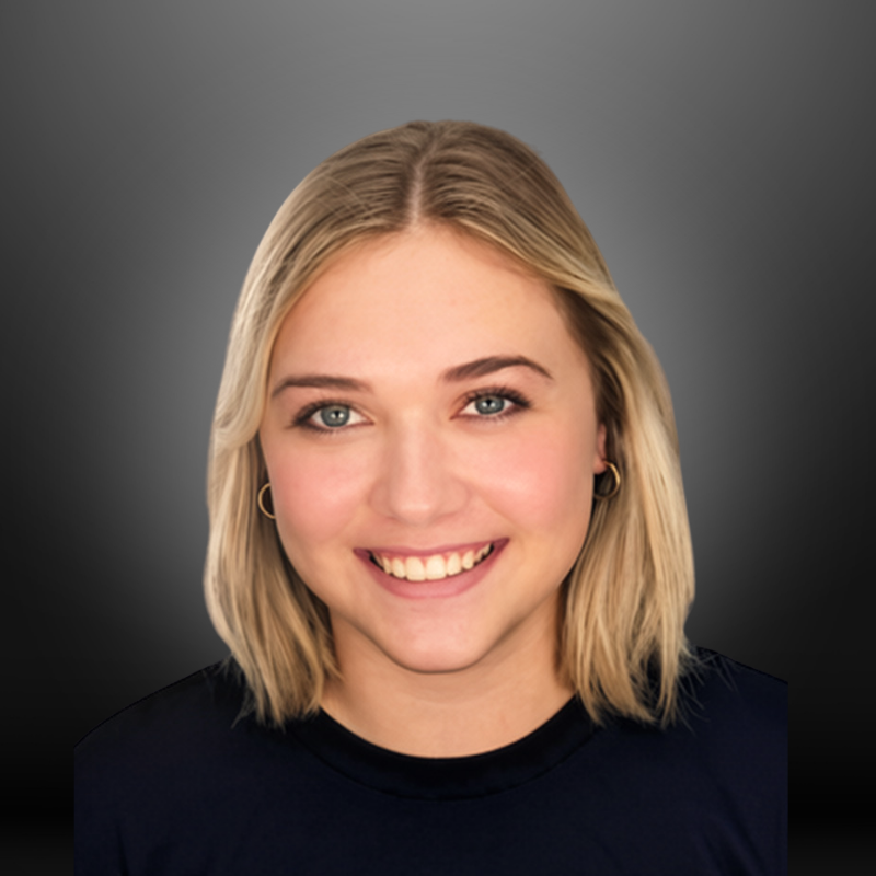 A young woman with shoulder-length blonde hair, blue eyes, and light skin, smiling and wearing a black shirt and small hoop earrings against a gray gradient background.
