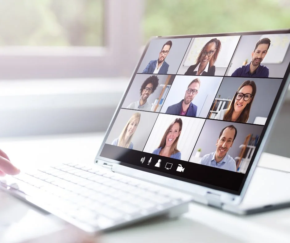 A laptop screen showing a video conference with nine diverse participants, each in their own video window during a virtual meeting.