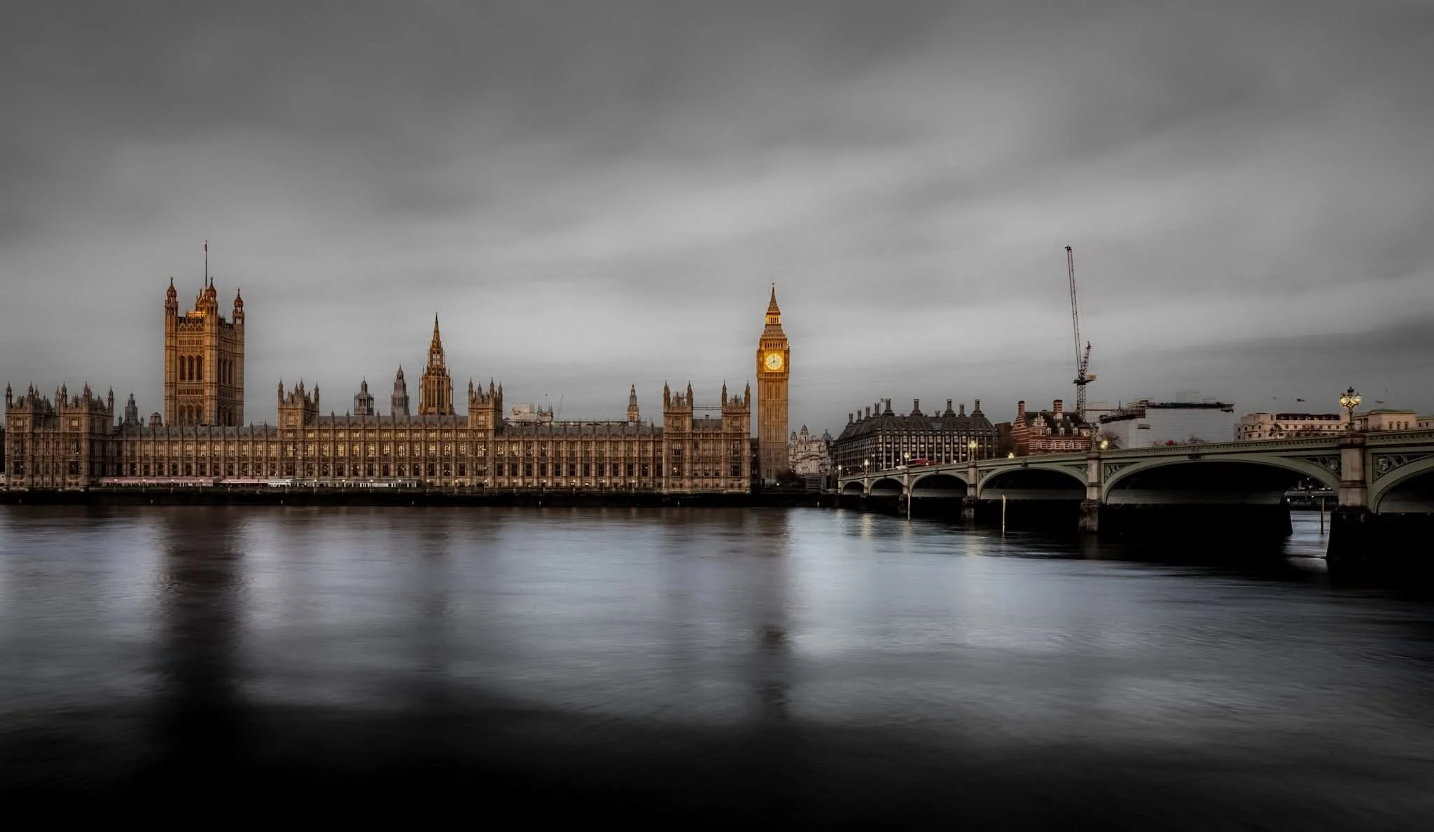 The image shows the Houses of Parliament and Big Ben in London, with a river in the foreground and a cloudy sky overhead.