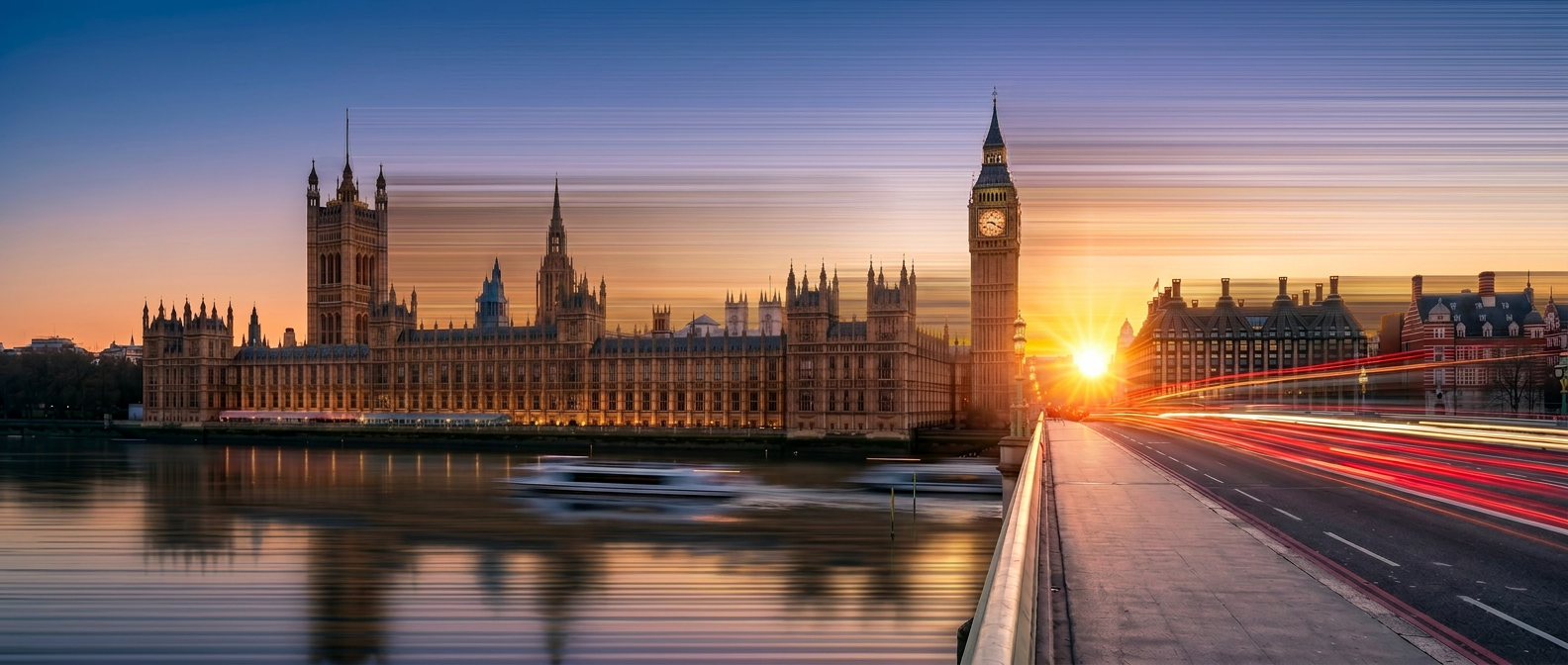 Sunset over the Houses of Parliament and Big Ben in London with light trails from moving vehicles on Westminster Bridge.