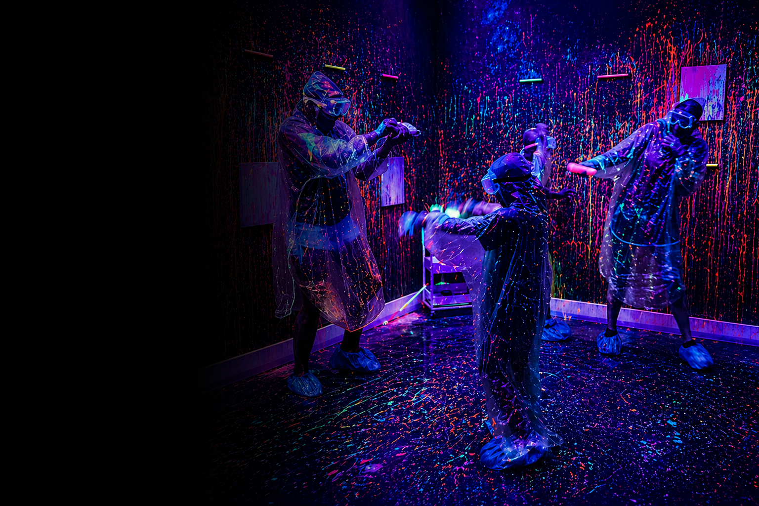 People wearing protective gear throwing neon paint in a splatter room