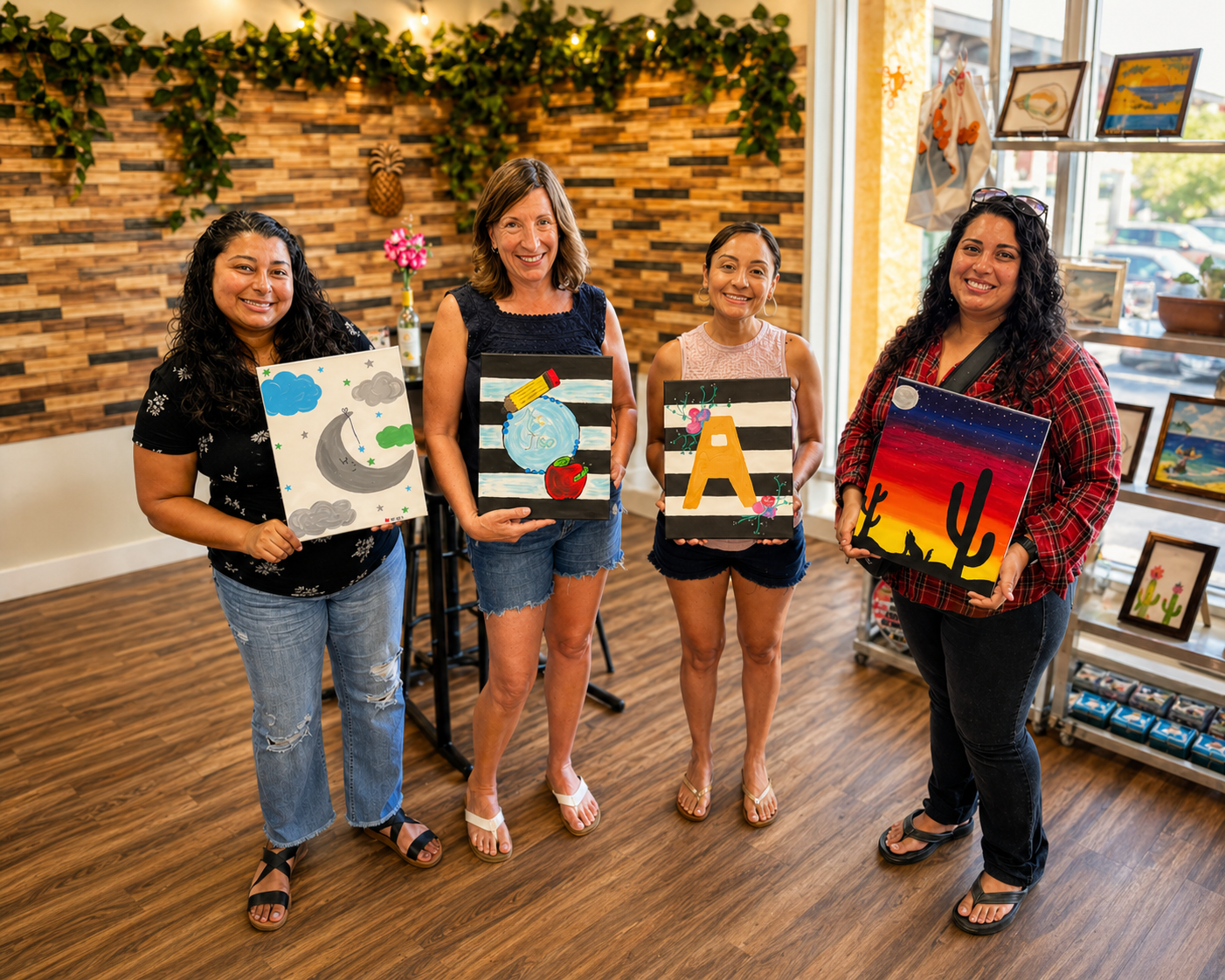 Women holding finished paintings after an art class in a studio