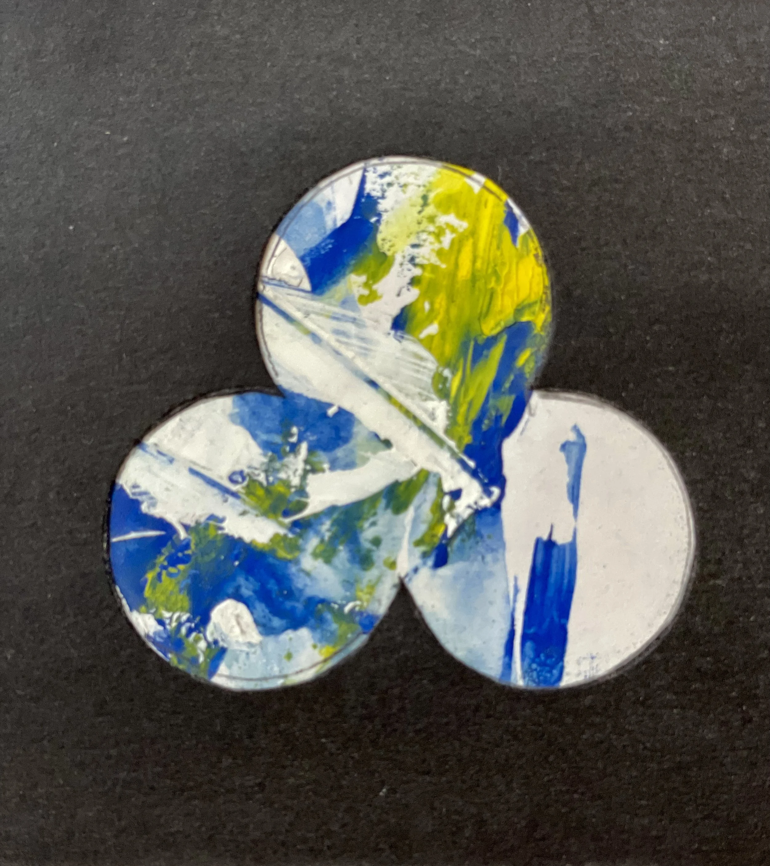 Drei runde Formen mit abstrakter Malerei in Blau, Gelb und Weiß auf schwarzem Hintergrund.