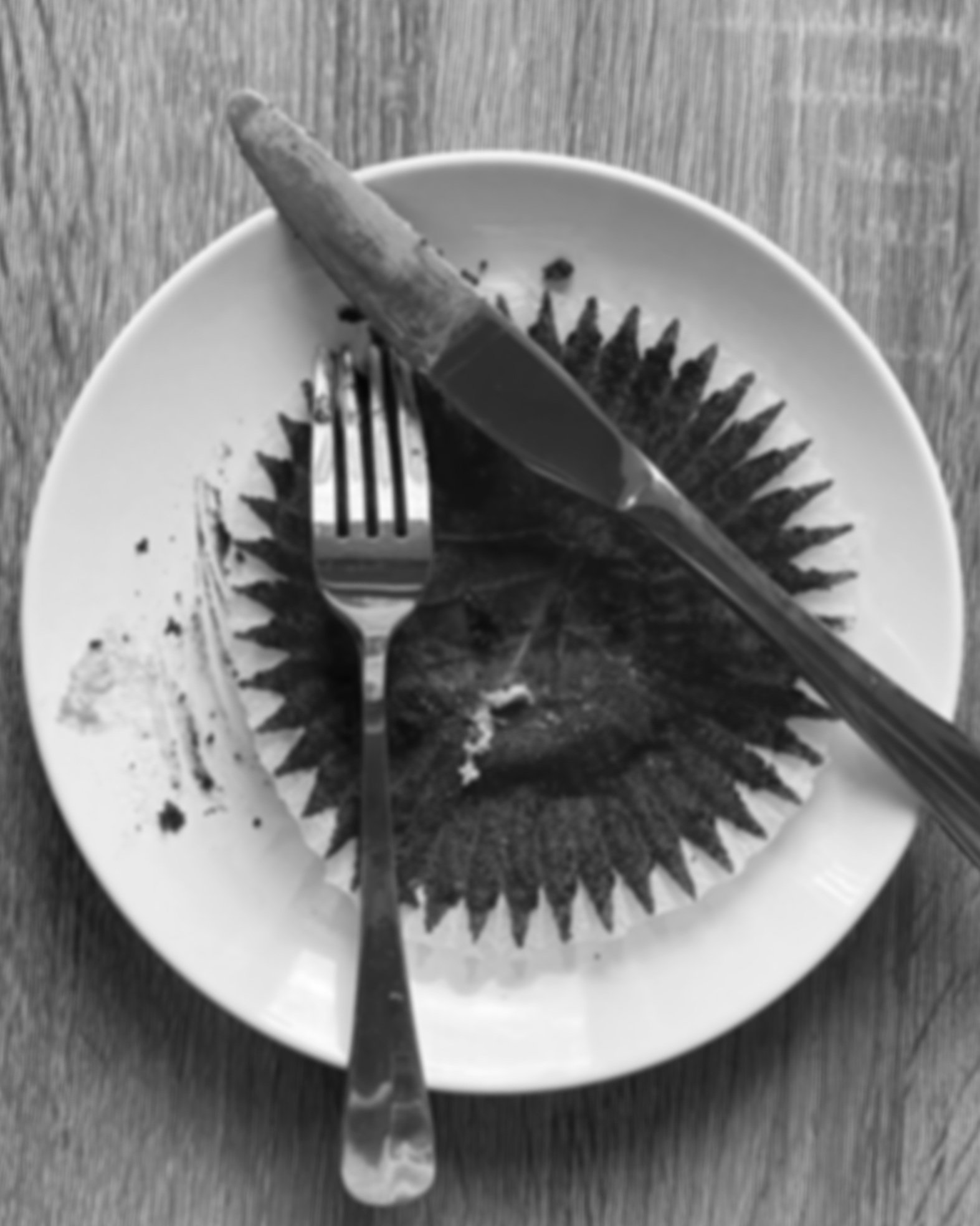 Red velvet cupcake wrapper with a dirty knife and fork placed on the plate.