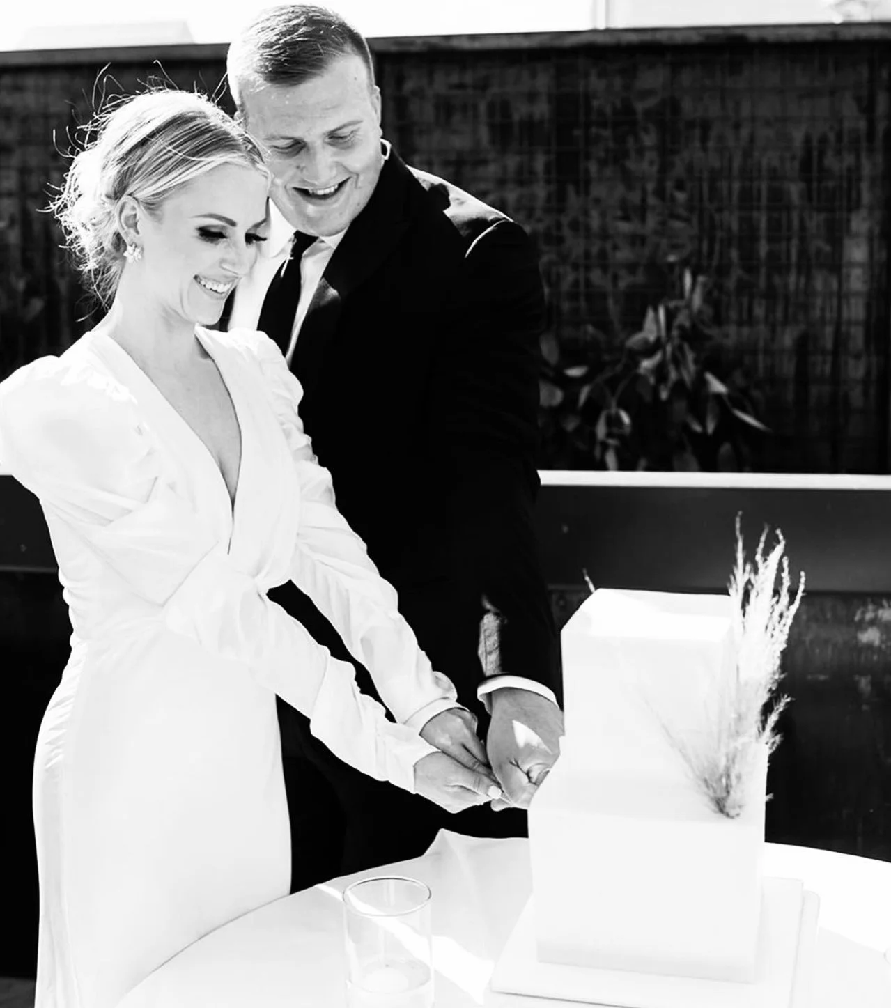Just married couple cut into their 2 tier square wedding cake.
